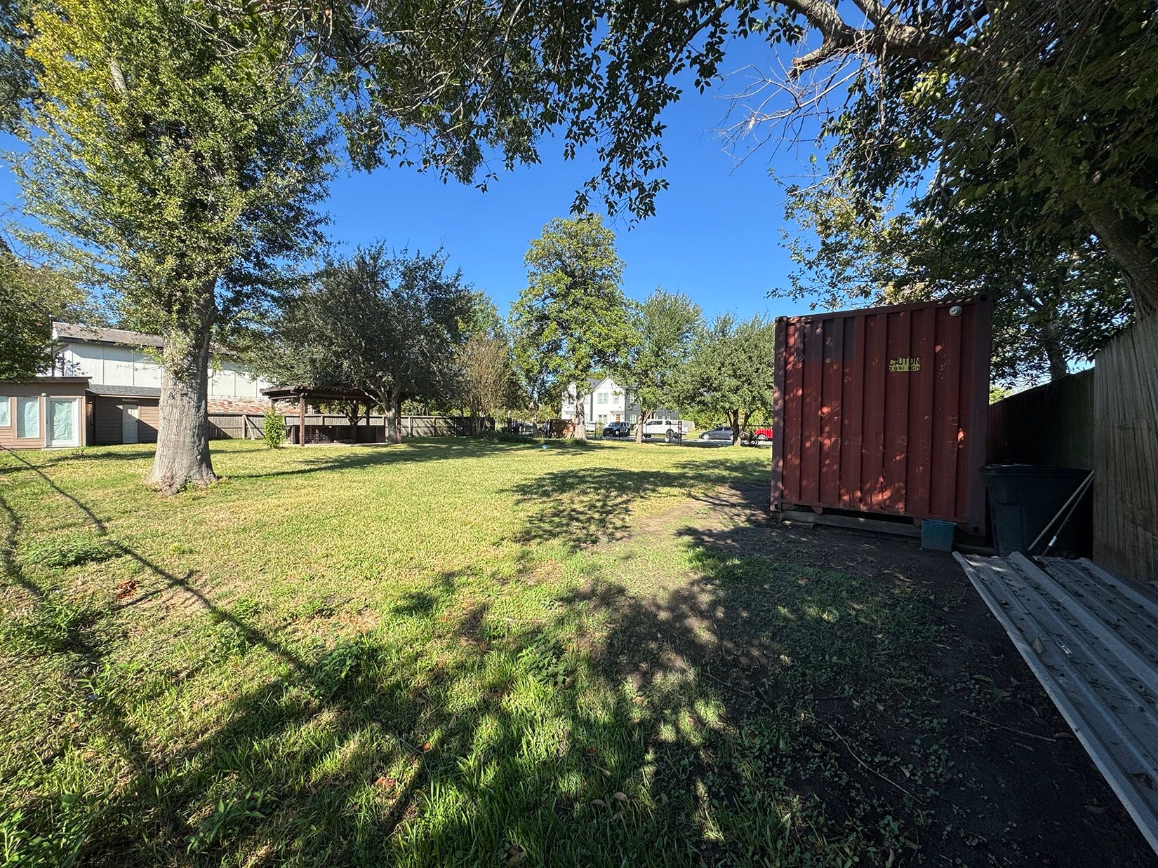 This photo showcases a spacious, grassy yard with scattered trees providing shade. The area offers a serene, open space ideal for outdoor activities.