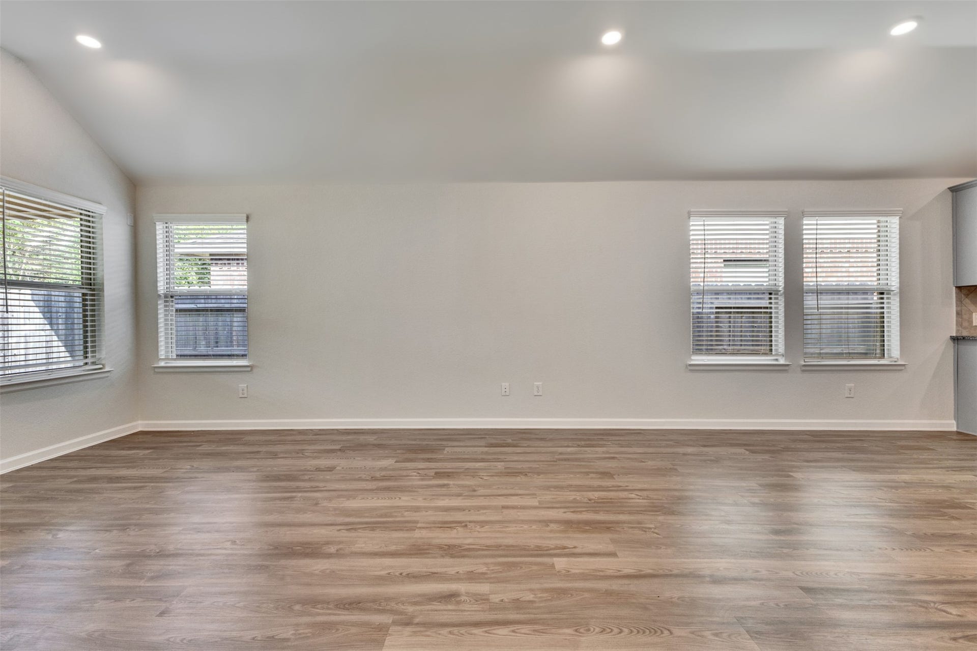 Spacious living area featuring vinyl plank flooring, abundant natural light, and recessed lighting.