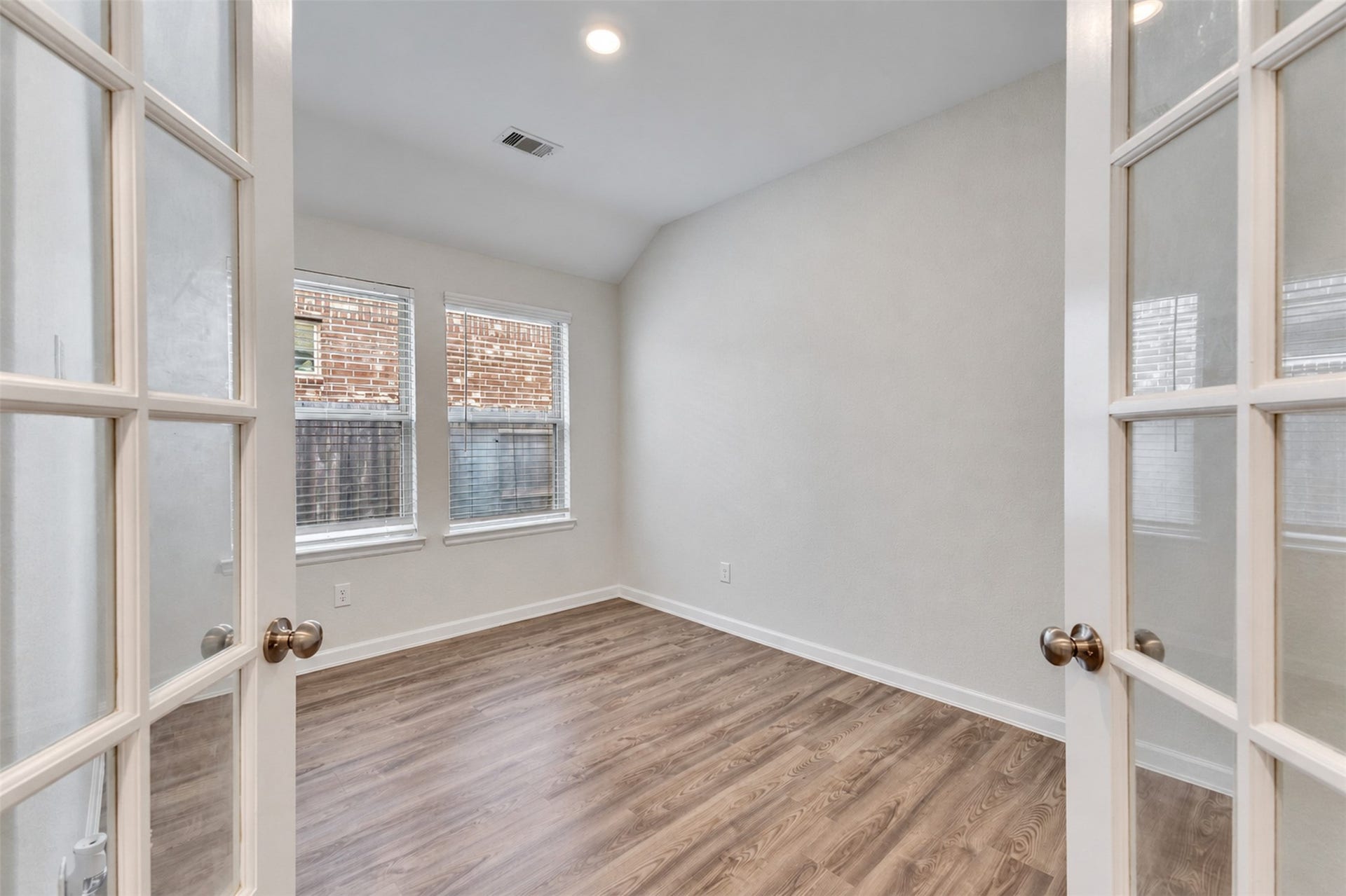 Private home office/study featuring French doors, vinyl plank flooring, and abundant natural light.