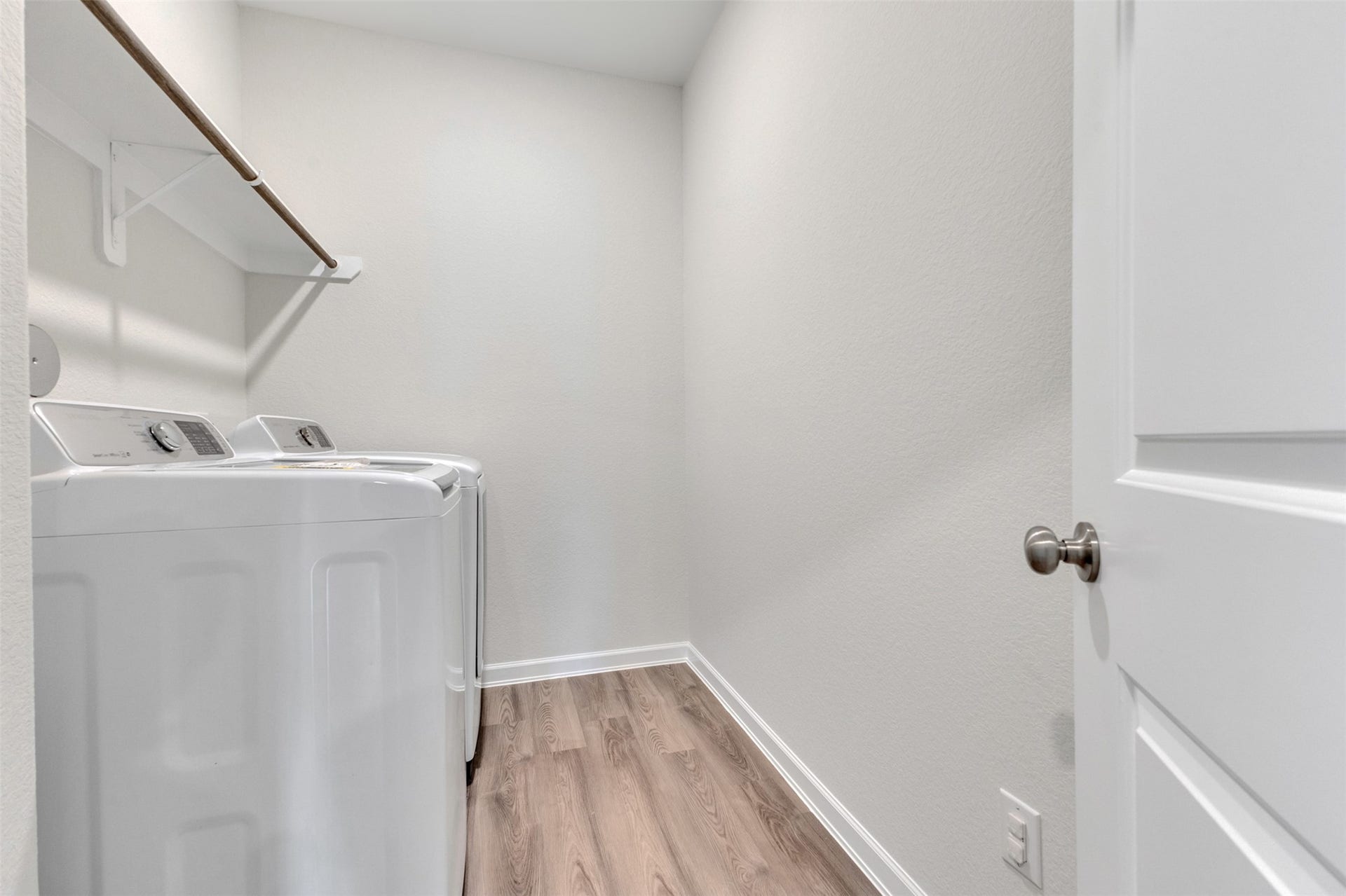 Indoor laundry room featuring washer and dryer, hanging rod, and additional storage space.