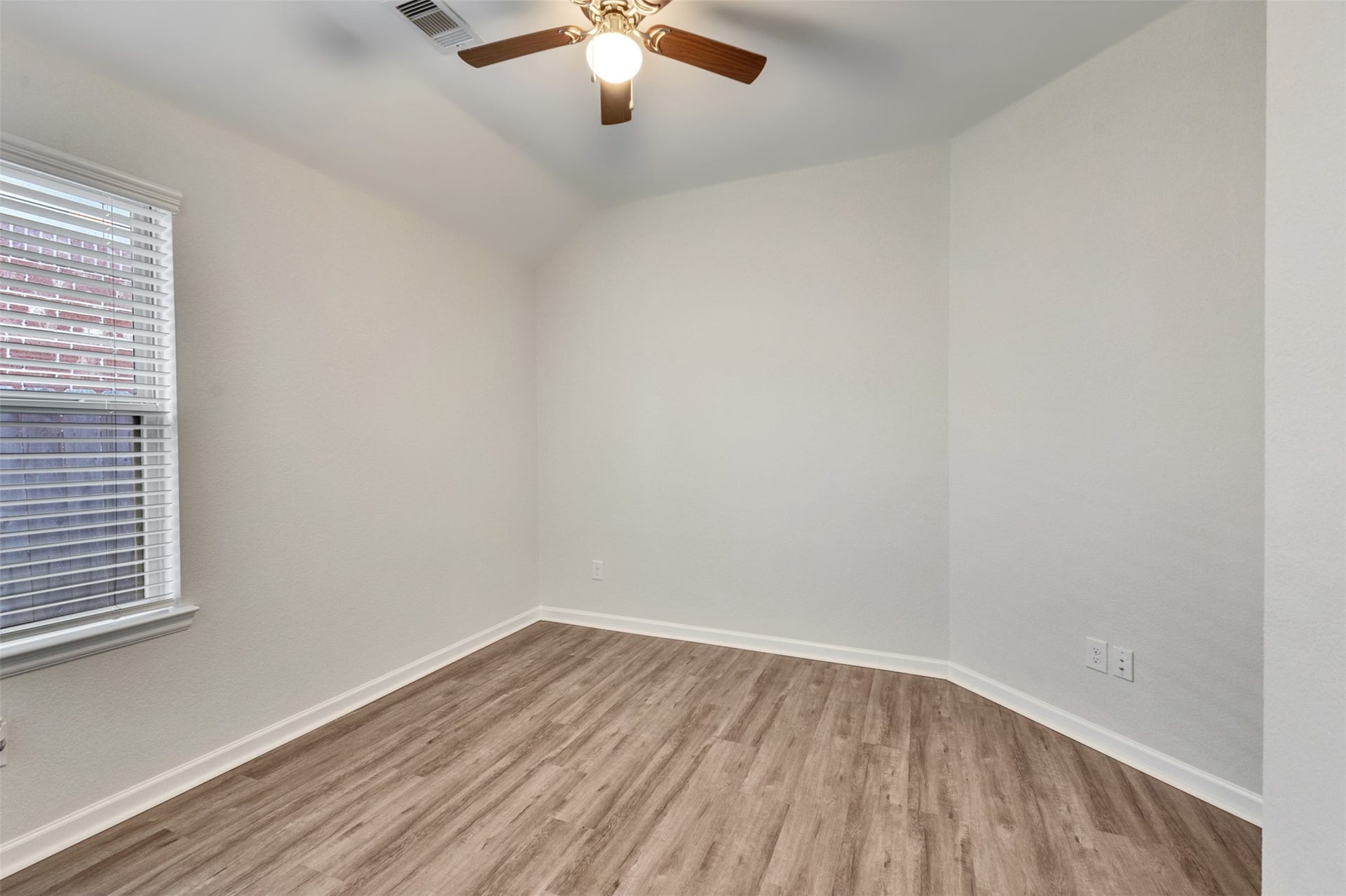 Secondary bedroom featuring fresh neutral paint, vinyl plank flooring, ceiling fan, and natural light.