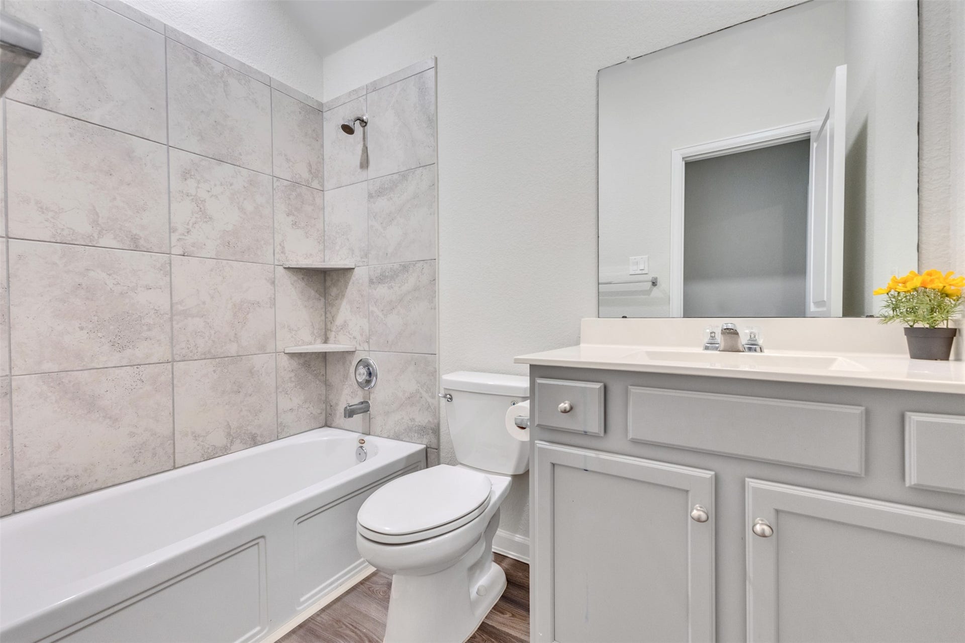 Secondary bathroom featuring a tub/shower combination with tile surround, vanity, and ample storage.