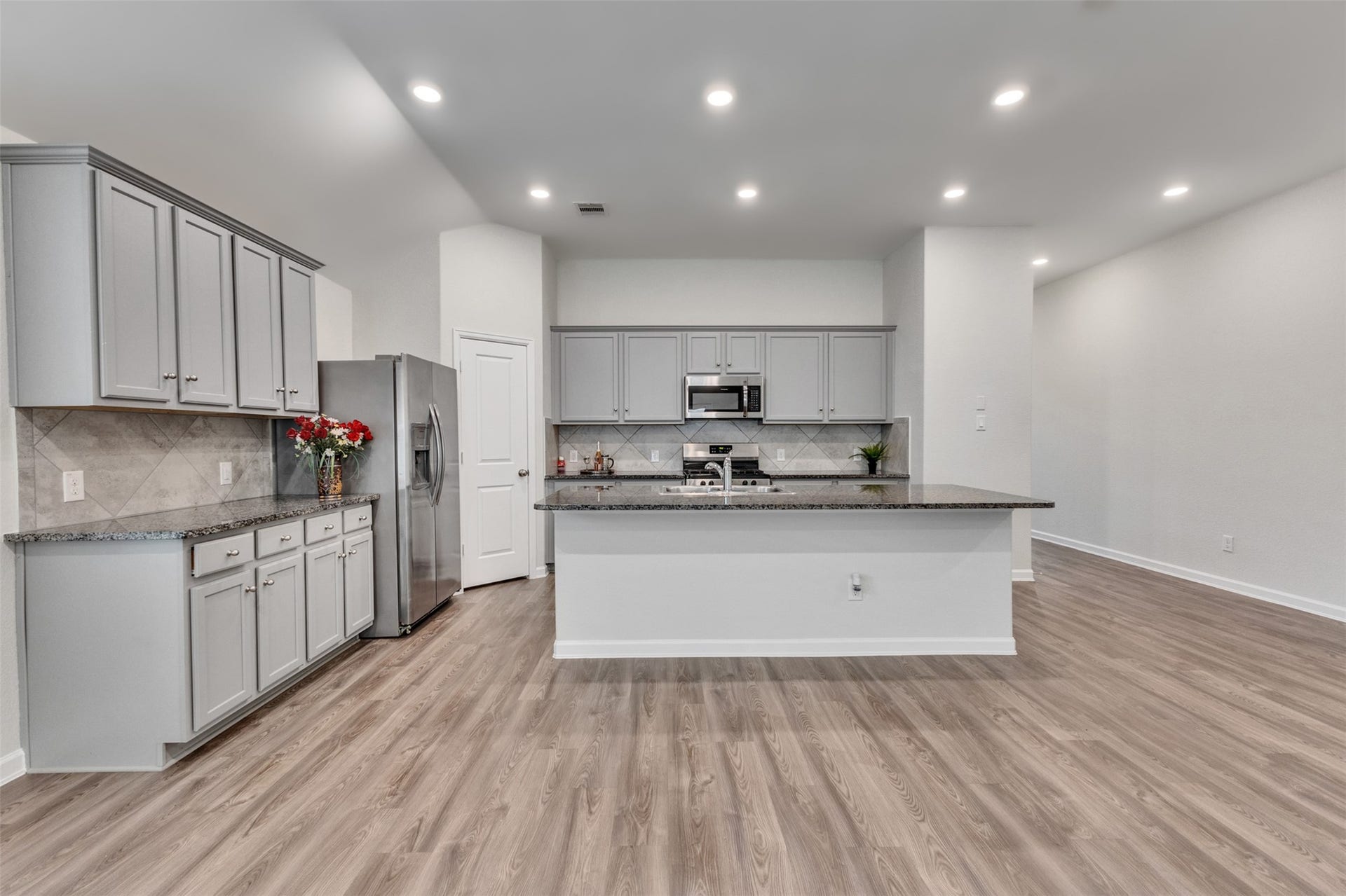 Spacious kitchen featuring granite countertops, abundant cabinetry, large breakfast bar, stainless steel appliances, and recessed lighting.