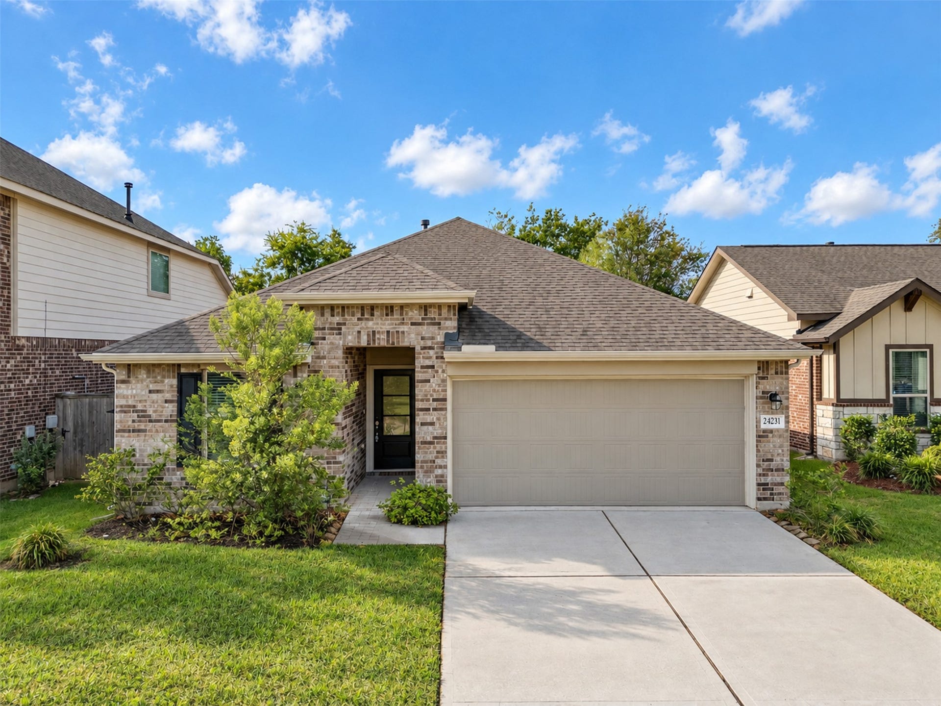 A charming one-story brick home with a two-car garage, welcoming covered entry, and landscaped front yard.