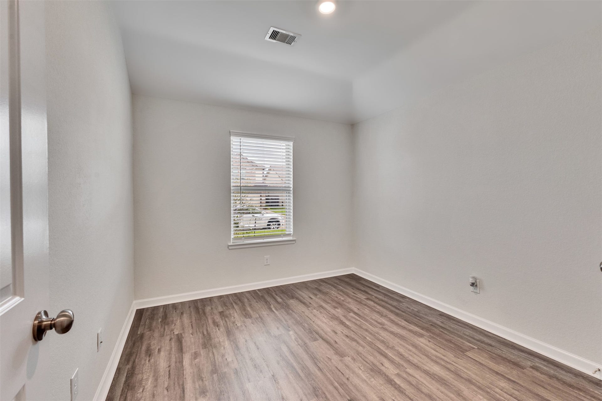 Secondary bedroom featuring fresh neutral paint, vinyl plank flooring, and natural light.