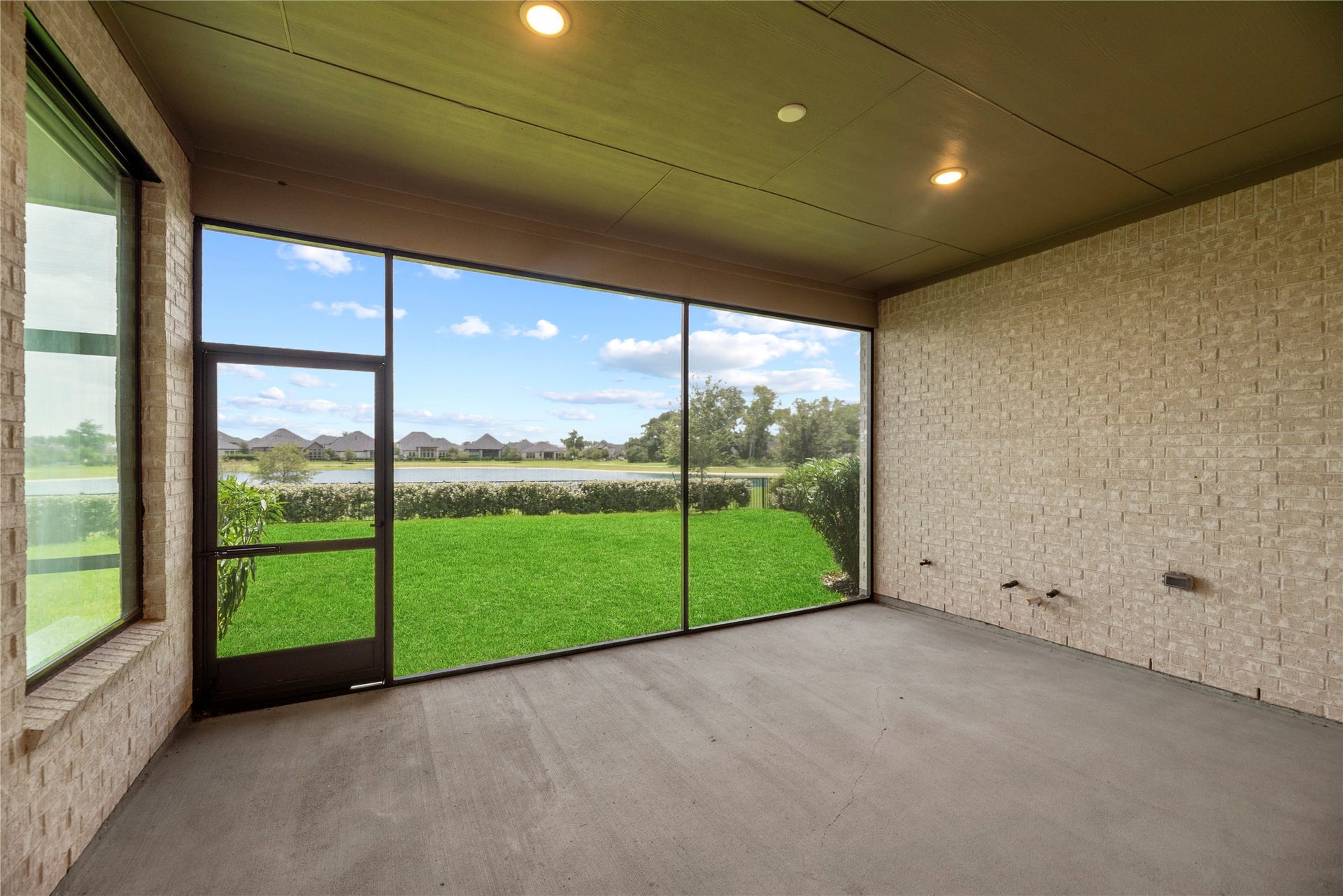 Enjoy year-round outdoor living on this screened back porch overlooking a lush green lawn and tranquil neighborhood lake.