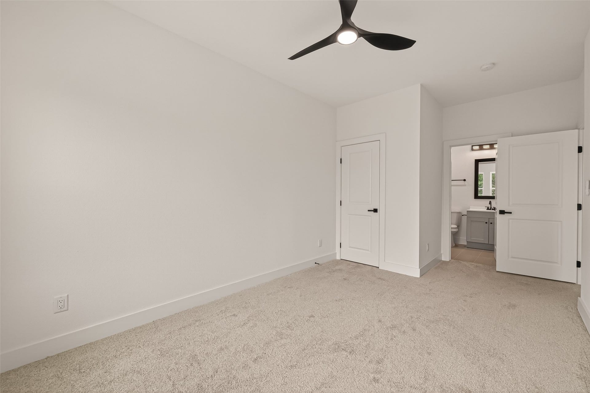 6808 Madrid Street, Houston, TX 77021 This bright bedroom features neutral walls and carpet, a modern ceiling fan, a closet, and an en-suite bathroom with sleek fixtures.