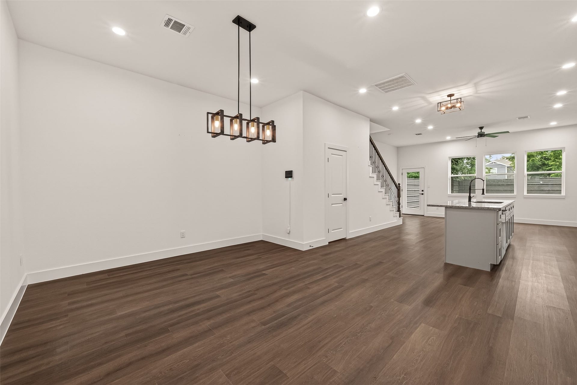 6808 Madrid Street, Houston, TX 77021 This open-concept living space features elegant engineer wood flooring, modern light fixtures, and a sleek kitchen island. The area is well-lit with recessed lighting and large windows, and there's easy access to the staircase.