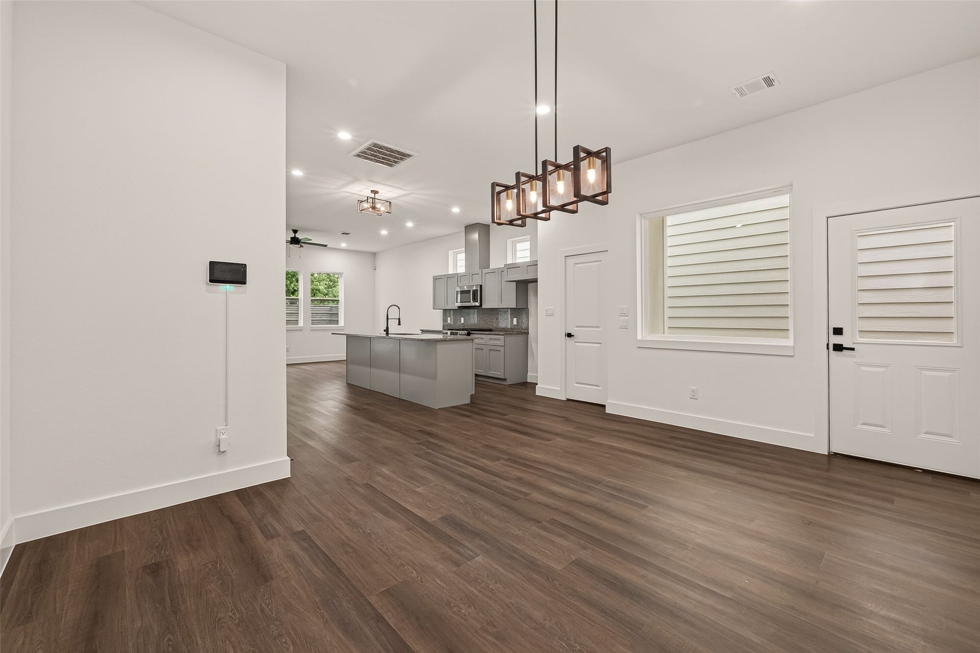 6808 Madrid Street, Houston, TX 77021 This modern open-concept living area features engineer wood flooring, a sleek kitchen with an island and stainless steel appliances, and ample natural light from large windows. Contemporary light fixtures add a stylish touch.