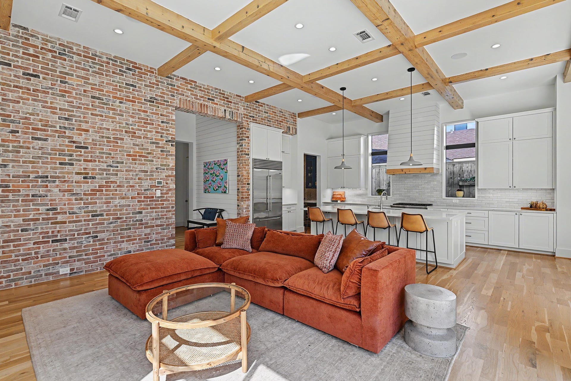 1605 Mcduffie Street, Houston, TX 77019 A textured brick accent wall and light-stained cedar beams add warmth and character to the sophisticated living space.