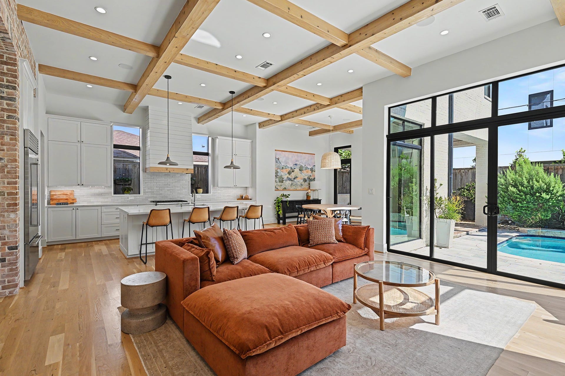 1605 Mcduffie Street, Houston, TX 77019 Cedar ceiling beams and expansive black-framed windows bring warmth and architectural presence to the open living area.