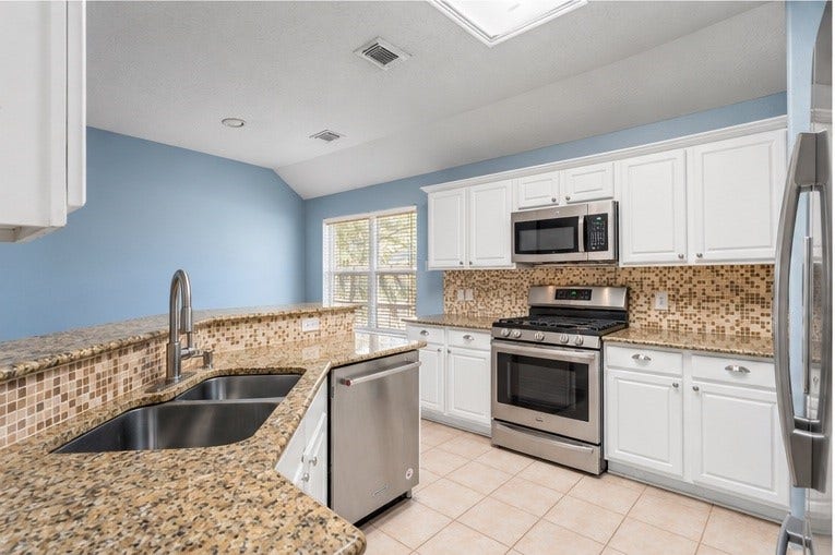 12902 Cascadia Knoll Court, Humble, TX 77346 Additional kitchen view featuring a stainless steel range and dishwasher, built-in microwave, white cabinetry, and granite countertops.