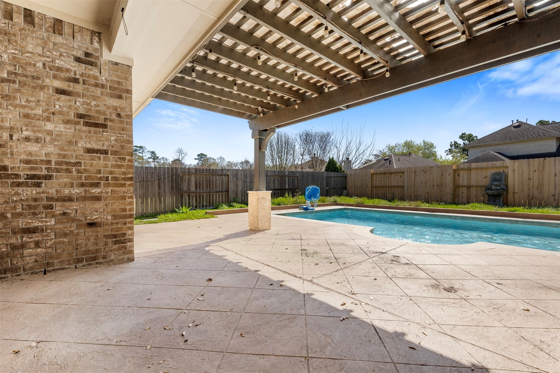 12902 Cascadia Knoll Court, Humble, TX 77346 Covered back patio overlooking the backyard and swimming pool, providing a shaded outdoor space for relaxing or entertaining.