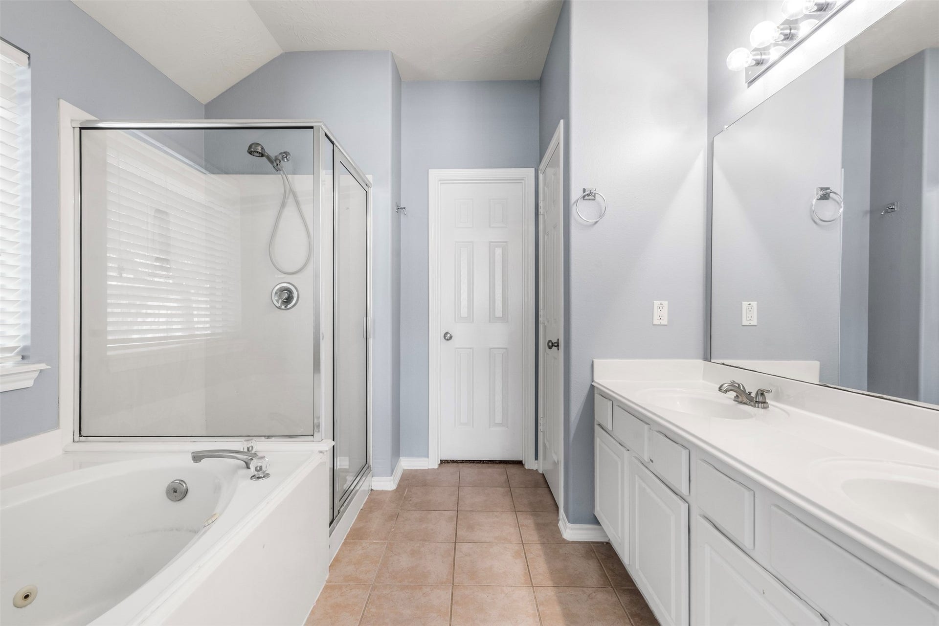 12902 Cascadia Knoll Court, Humble, TX 77346 Primary bathroom featuring a long dual-sink vanity with generous counter space, white cabinetry, large mirrors, and a separate tub and shower area.