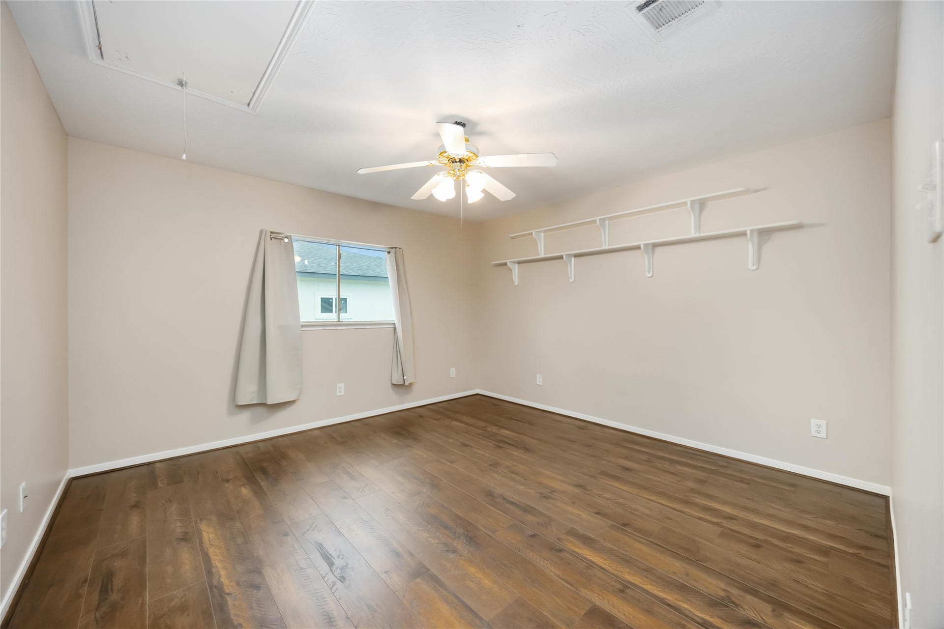 5498 Appleblossom Lane, Friendswood, TX 77546 This room features a clean, minimalist design with hardwood floors, neutral walls, a ceiling fan, and natural light from a window with simple curtains. Built-in shelves provide extra storage space.