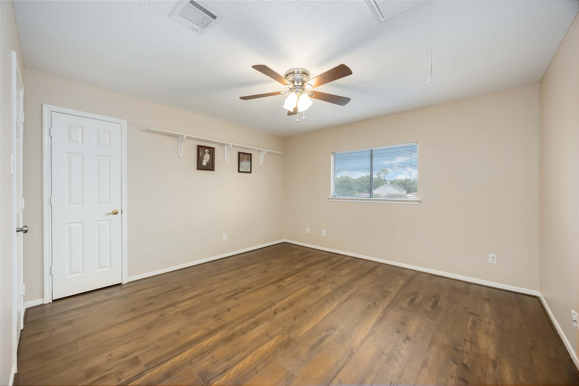 5498 Appleblossom Lane, Friendswood, TX 77546 This spacious room features hardwood flooring, neutral walls, and a ceiling fan. It has a large window for natural light and a closet with a white door, making it ideal for a bedroom or office.