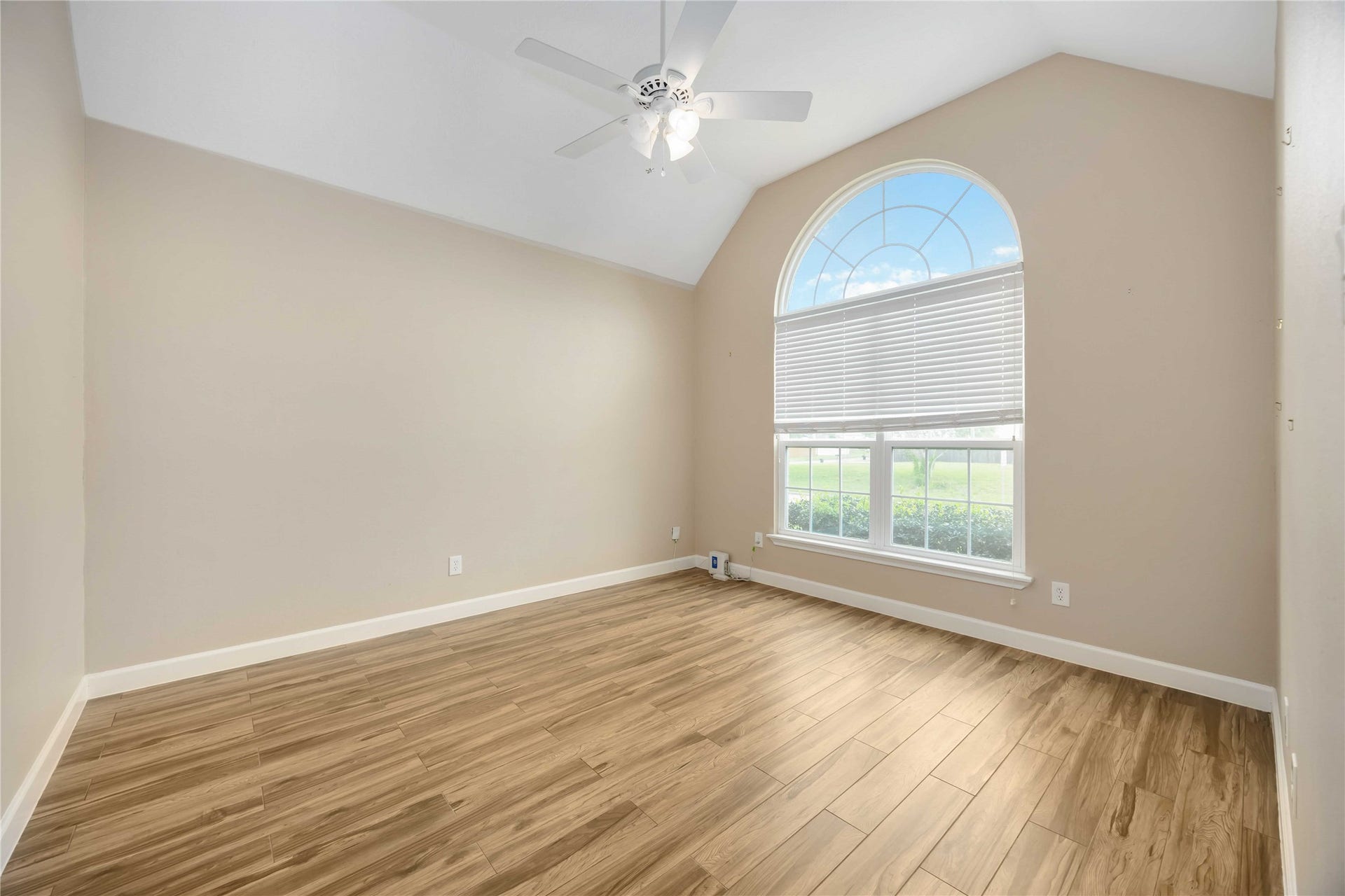 5498 Appleblossom Lane, Friendswood, TX 77546 This bright room is the study and it offers vaulted ceiling, neutral walls, and wood-look flooring. Features a large arched window with blinds and a ceiling fan.