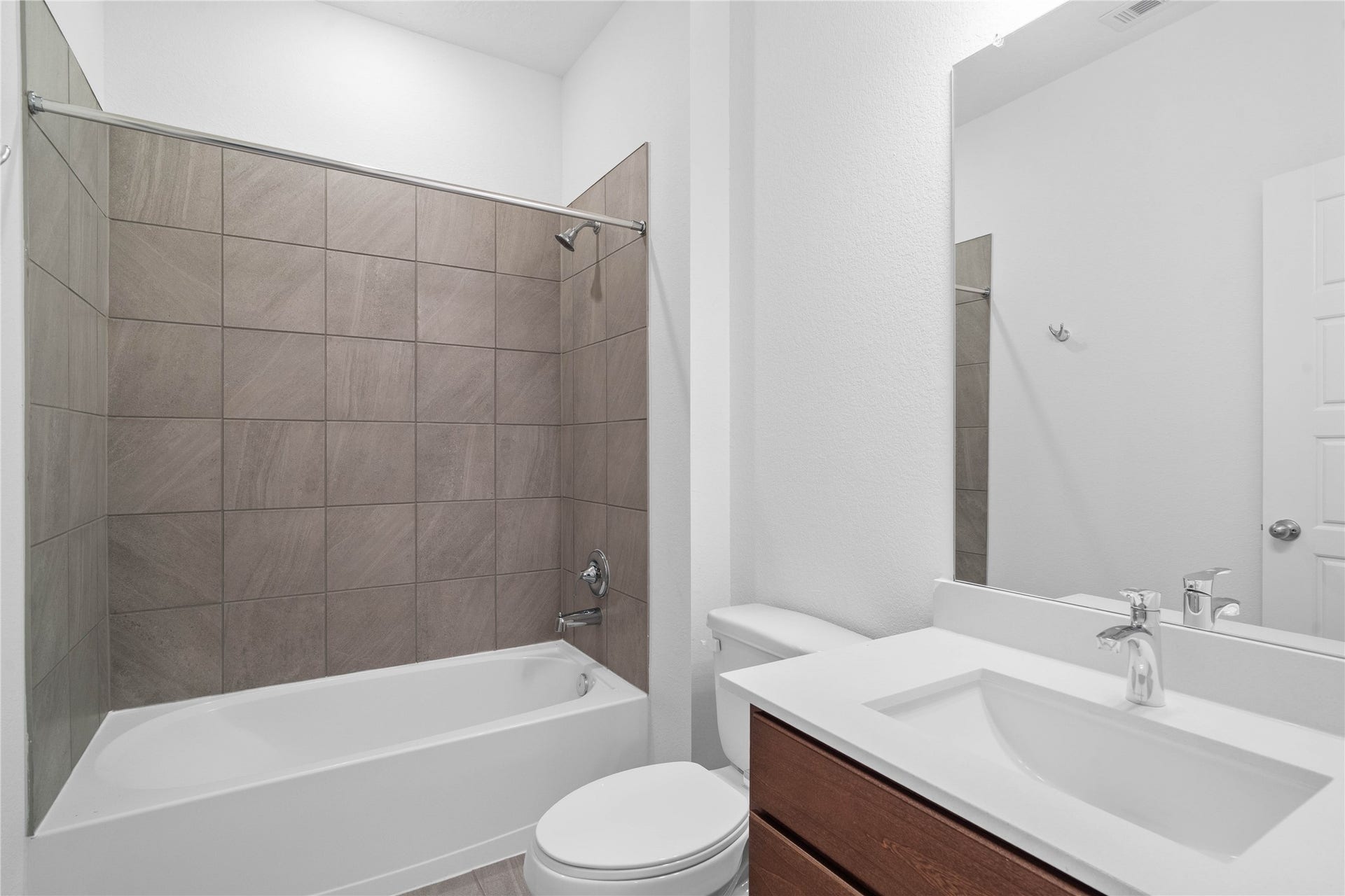 5619 Blackbird Lane, Hitchcock, TX 77563 The secondary bathroom showcases tile flooring, a bath/shower combo with a Daltile tile surround, a 30" vanity with a stunning light countertop, a mirror, sleek fixtures, and contemporary finishes throughout.