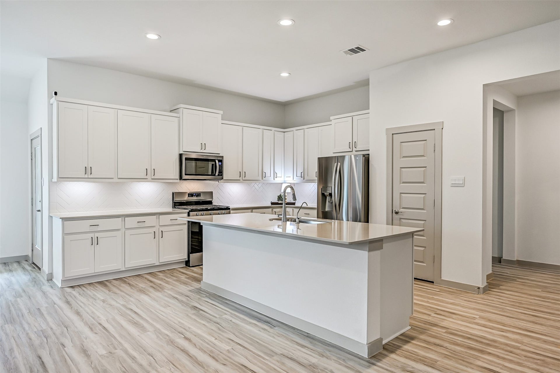 6204 Red Oak Court, League City, TX 77573 Crisp white cabinetry stretches across the kitchen, complemented by sleek countertops, stainless appliances and a herringbone-pattern tile backsplash. The oversized island adds an abundance of prep space and storage.