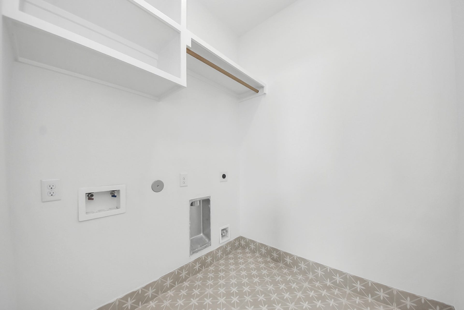 923 Fisher Street, #E, Houston, TX 77018 This bright laundry room combines style and function, with washer and dryer hookups, open shelving, and patterned tile flooring, making daily chores organized and efficient.