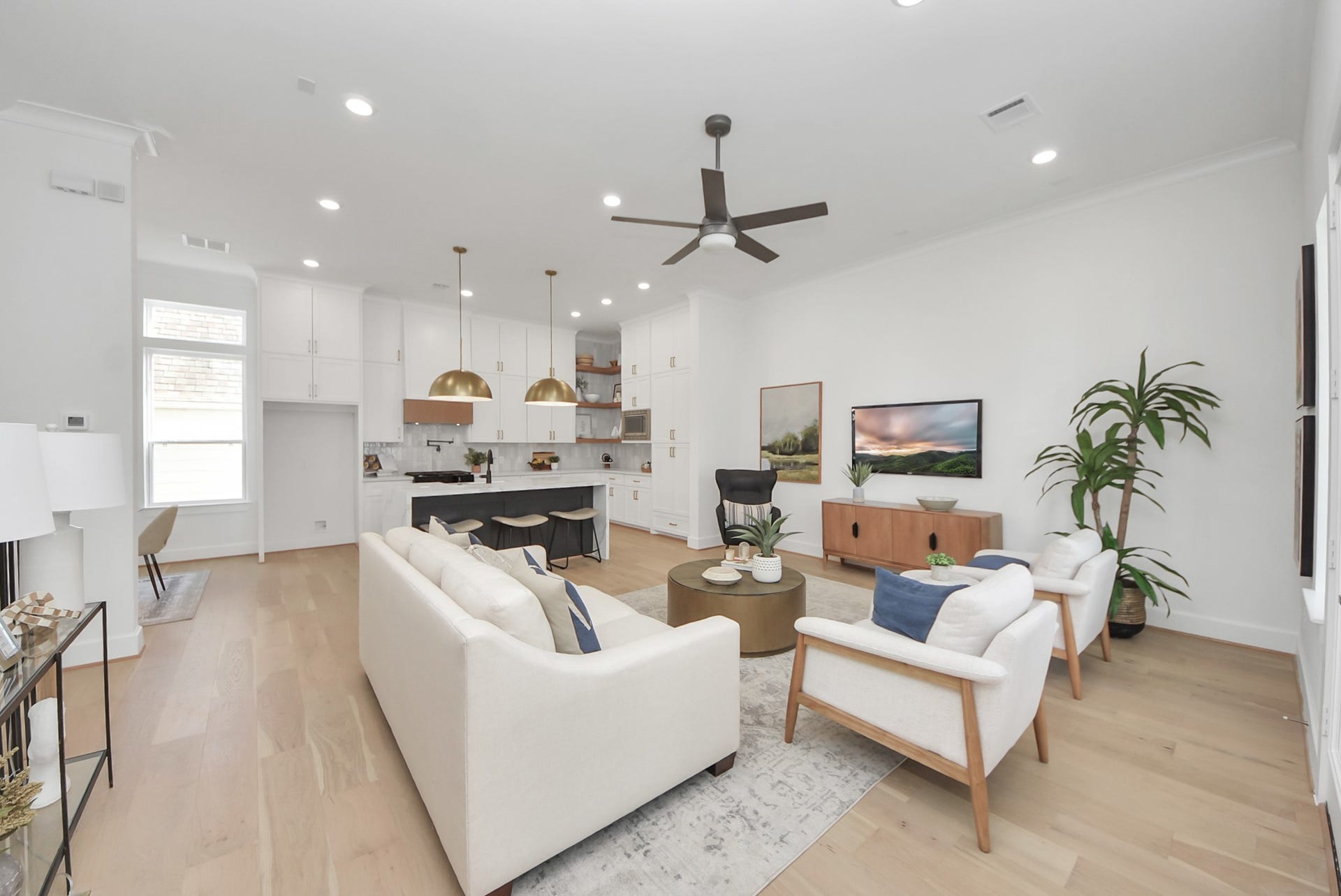 923 Fisher Street, #E, Houston, TX 77018 Welcome to this modern, open-concept living area, where light wood flooring and abundant natural light create a bright and inviting atmosphere. The sleek kitchen, with white cabinetry and gold pendant lights, flows seamlessly into a cozy living space featuring contemporary furniture and a ceiling fanperfect for entertaining or relaxing with family and friends.