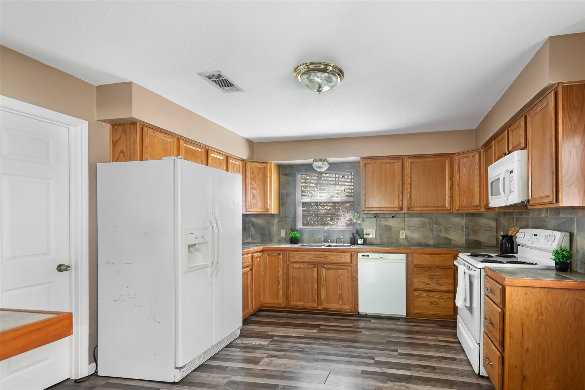 23304 E Community Drive, New Caney, TX 77357 Functional kitchen with ample cabinetry, white appliances and wood-look flooring.