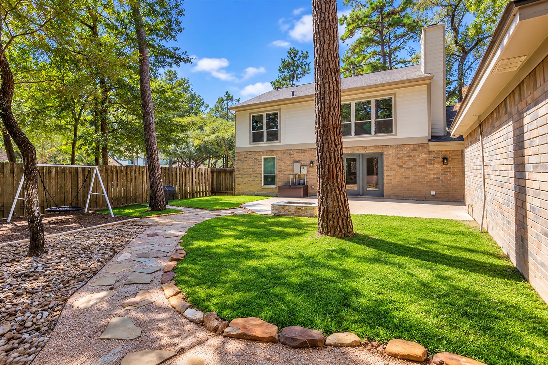 2 Tall Sky Place, The Woodlands, TX 77381 Large backyard with shade, firepit, and stone path walkway