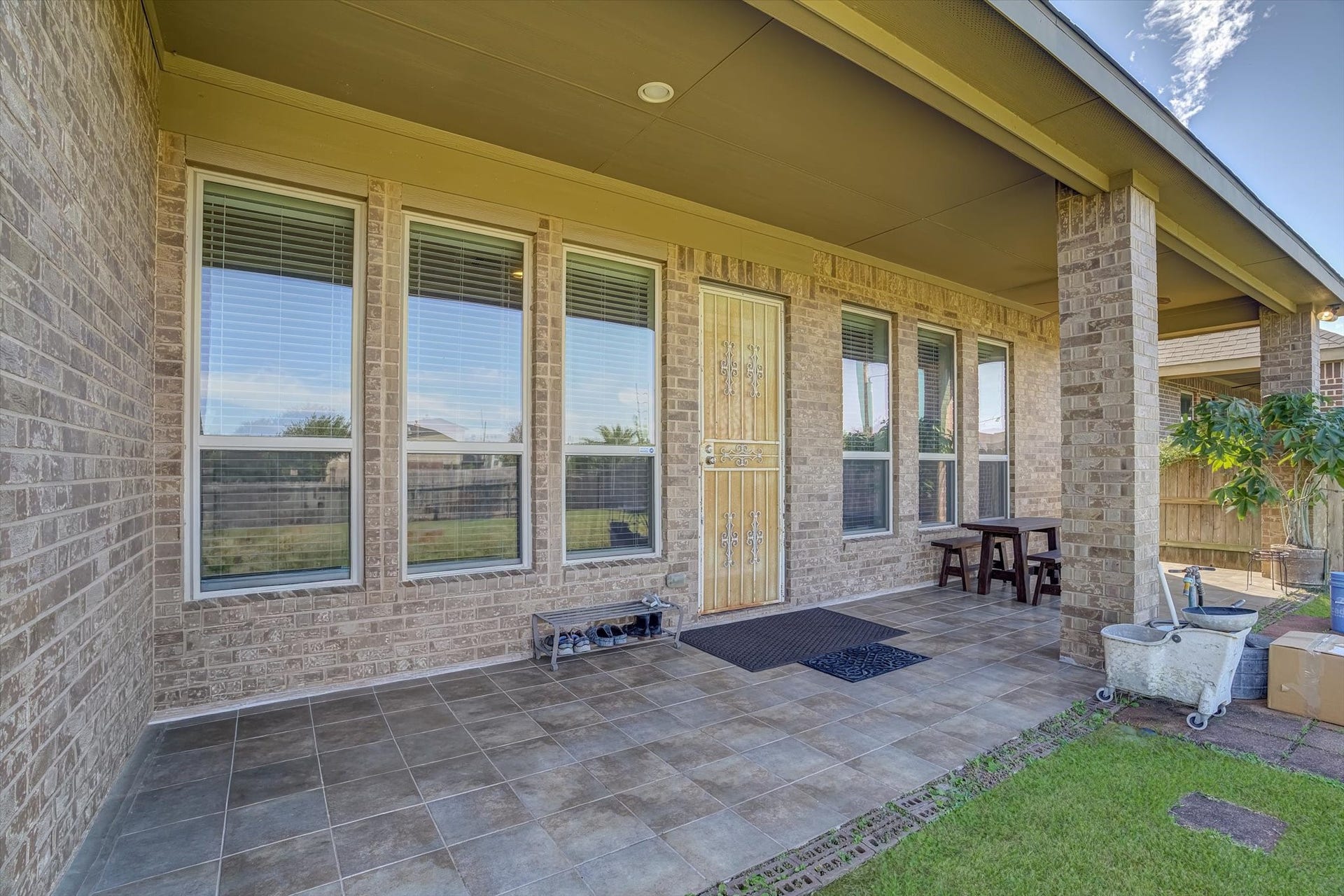 20302 Bandera Lake Lane, Richmond, TX 77407 Charming covered patio with elegant tile flooring, perfect for outdoor relaxation and entertaining, featuring large windows that offer abundant natural light.