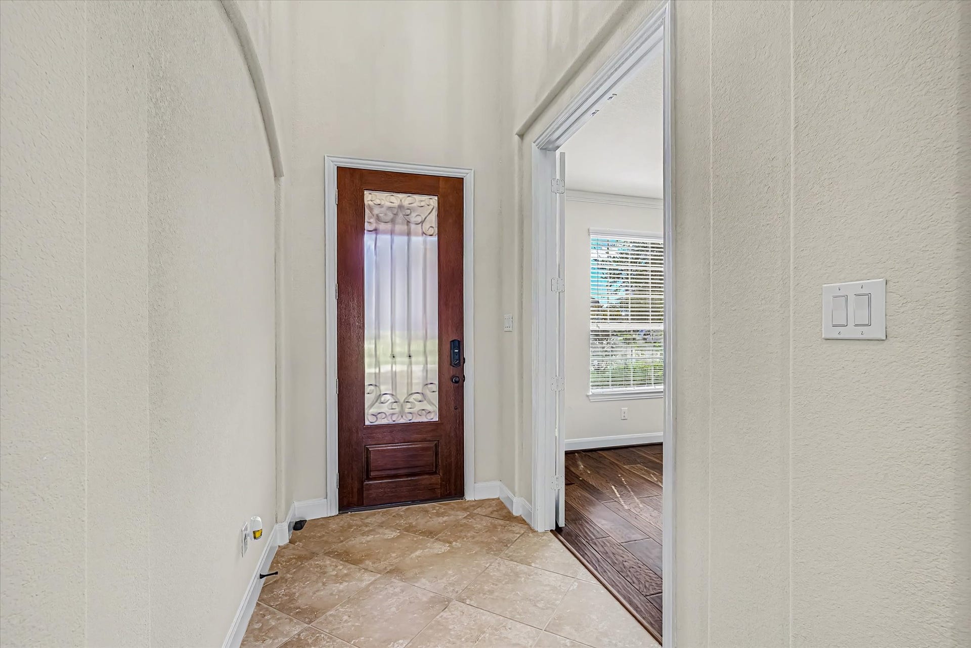 20302 Bandera Lake Lane, Richmond, TX 77407 Elegant entryway featuring a decorative wooden door and tiled flooring, leading to home office with large windows and rich wood flooring.