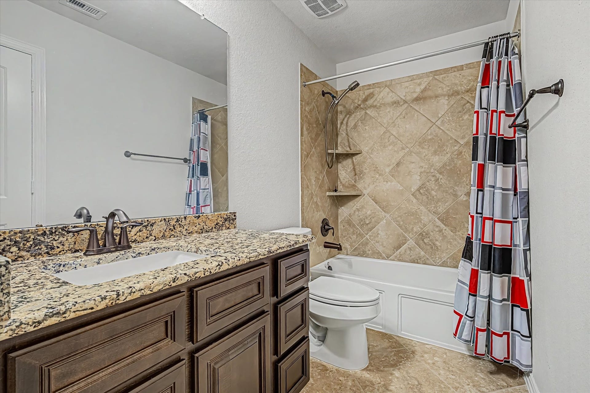 20302 Bandera Lake Lane, Richmond, TX 77407 Elegant secondary bathroom featuring a granite countertop, rich wood cabinetry, and a tiled shower.