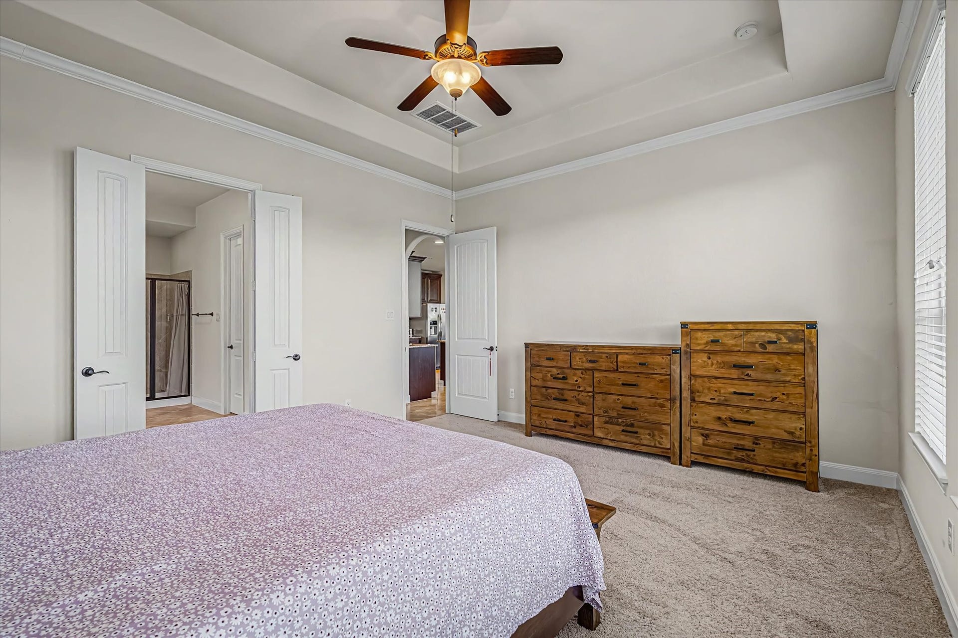 20302 Bandera Lake Lane, Richmond, TX 77407 Spacious bedroom featuring a cozy carpet, elegant tray ceiling with a fan, and abundant natural light from large windows.