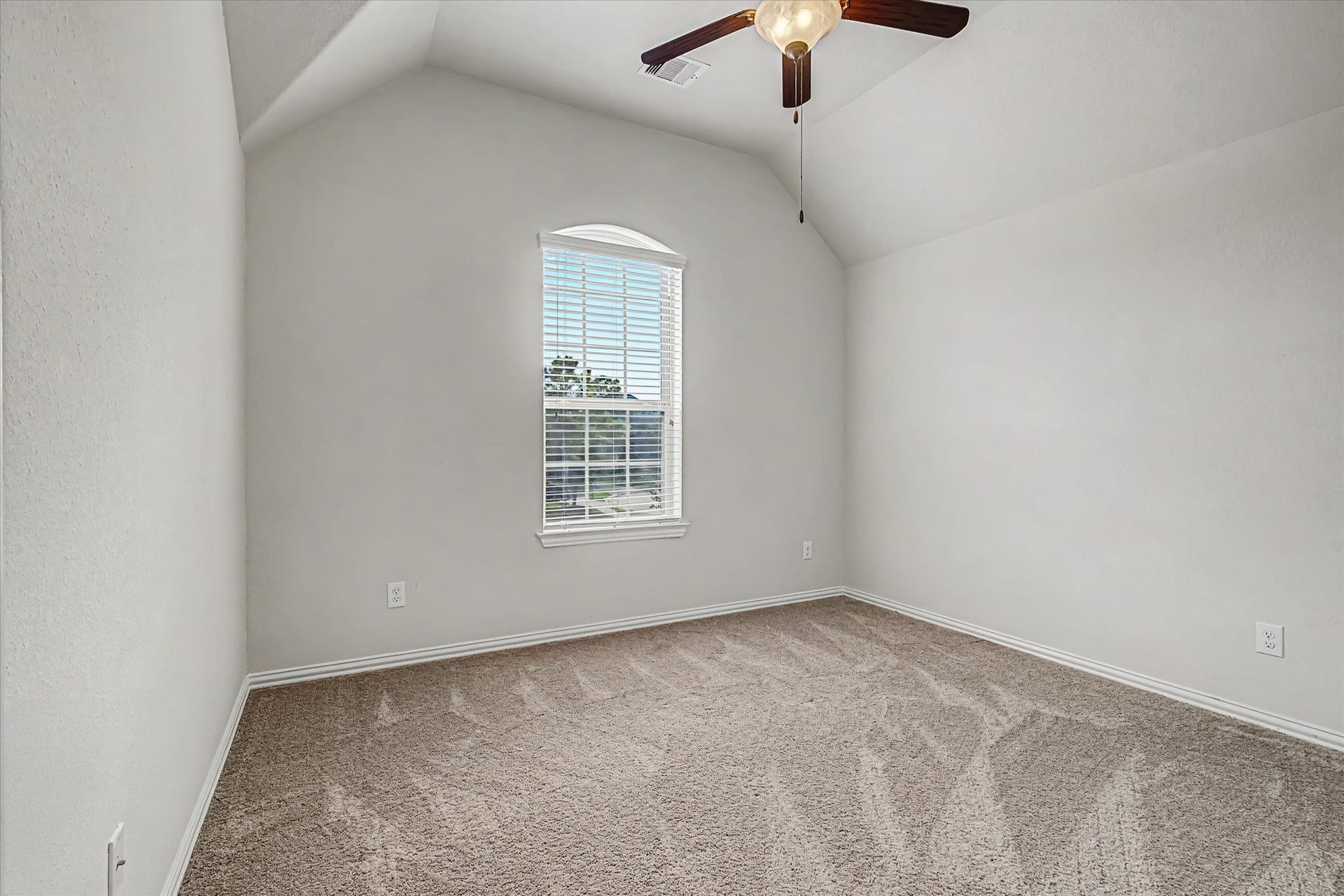 20302 Bandera Lake Lane, Richmond, TX 77407 Cozy bedroom featuring a vaulted ceiling, plush carpet, and a large window with natural light, complemented by a stylish ceiling fan.