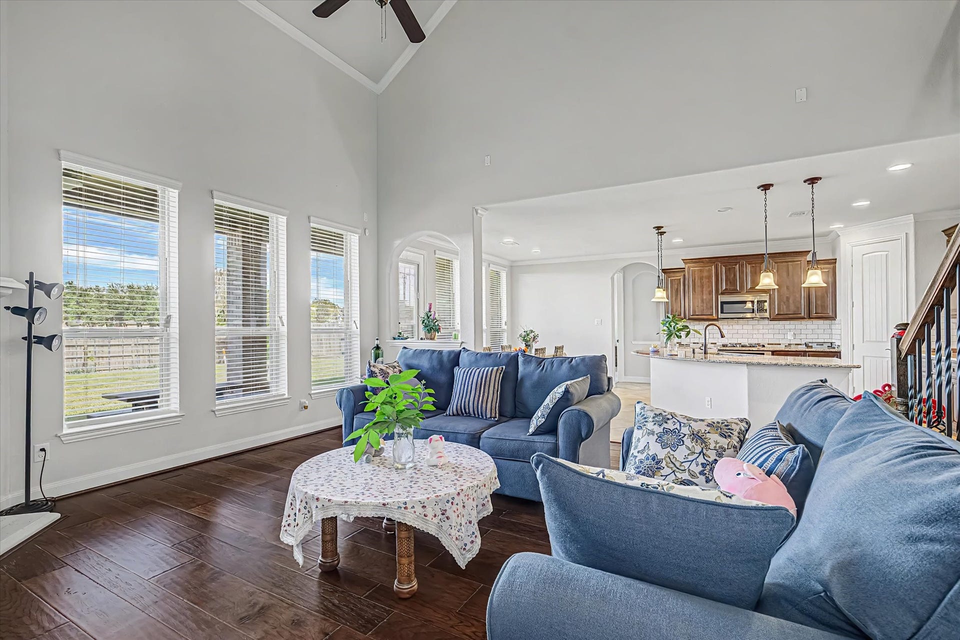 20302 Bandera Lake Lane, Richmond, TX 77407 Spacious open-concept living area with high ceilings, abundant natural light from large windows flowing into a modern kitchen with warm wood cabinetry and elegant pendant lighting.