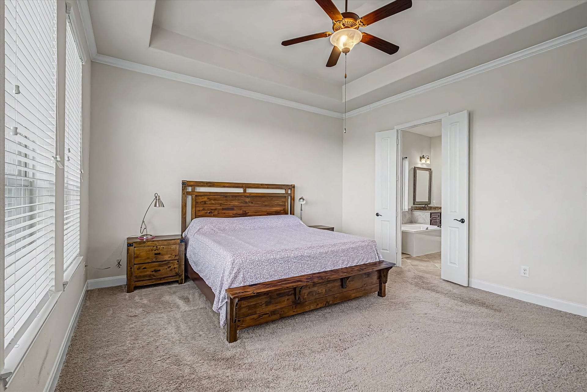 20302 Bandera Lake Lane, Richmond, TX 77407 Spacious primary bedroom with plush carpeting, crown molding, and a ceiling fan, featuring direct access to a bright en-suite bathroom.
