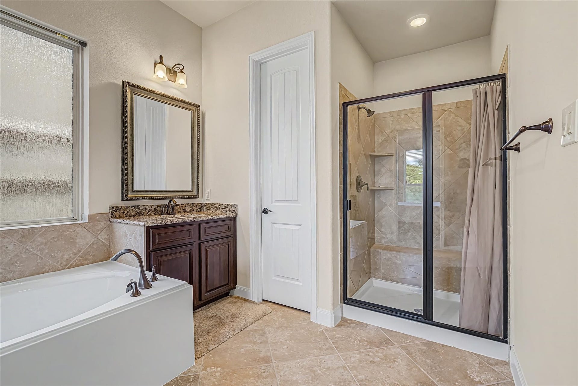 20302 Bandera Lake Lane, Richmond, TX 77407 Luxurious bathroom featuring a spacious glass-enclosed shower, elegant granite-topped vanity, and inviting soaking tub, complemented by warm tile flooring.