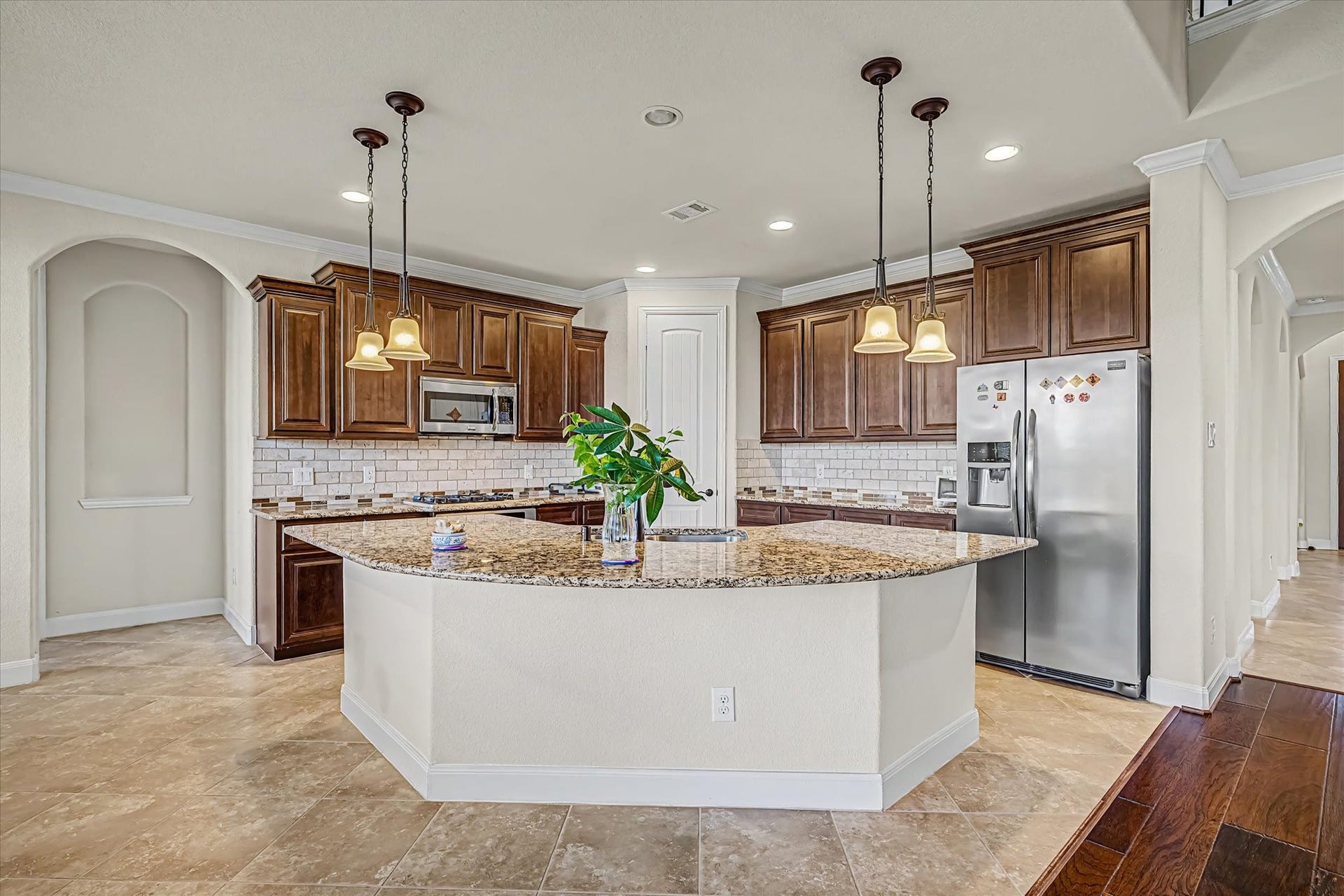 20302 Bandera Lake Lane, Richmond, TX 77407 A spacious kitchen with elegant granite countertops, rich wooden cabinetry, and modern stainless steel appliances, illuminated by stylish pendant lighting.