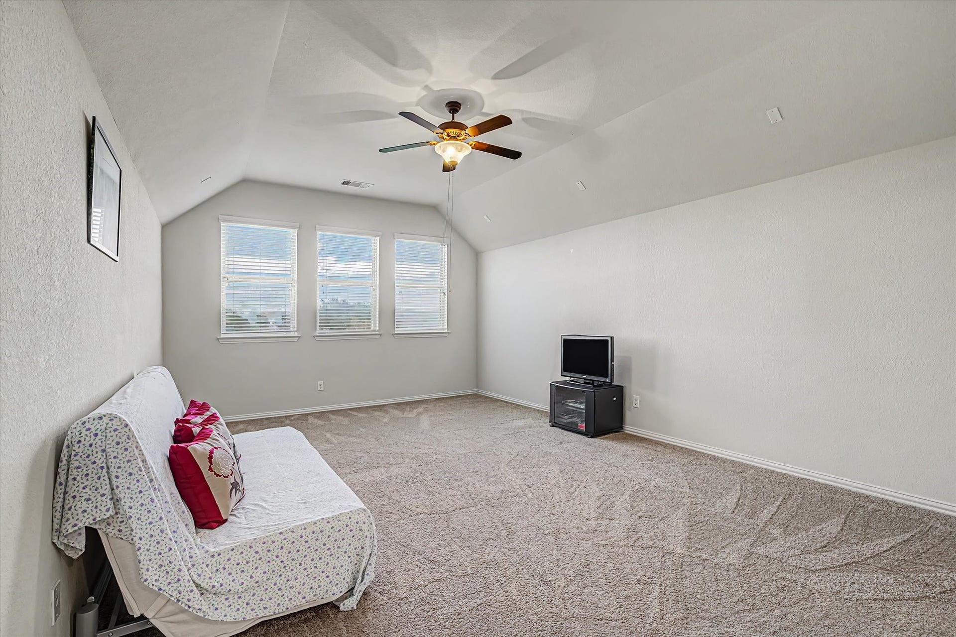 20302 Bandera Lake Lane, Richmond, TX 77407 Spacious and bright game room area with plush carpeting, featuring a cozy seating arrangement and a ceiling fan, perfect for relaxation or entertainment.