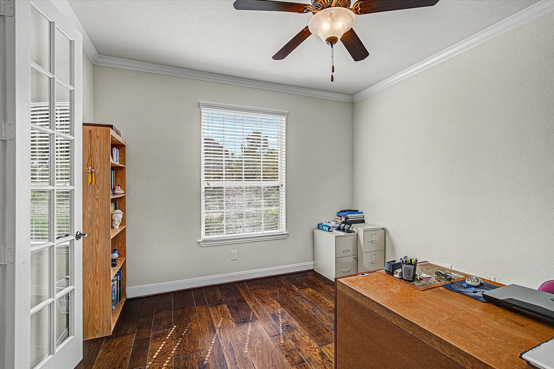 20302 Bandera Lake Lane, Richmond, TX 77407 Bright home office with elegant French doors, rich hardwood floors, and a ceiling fan for comfort.