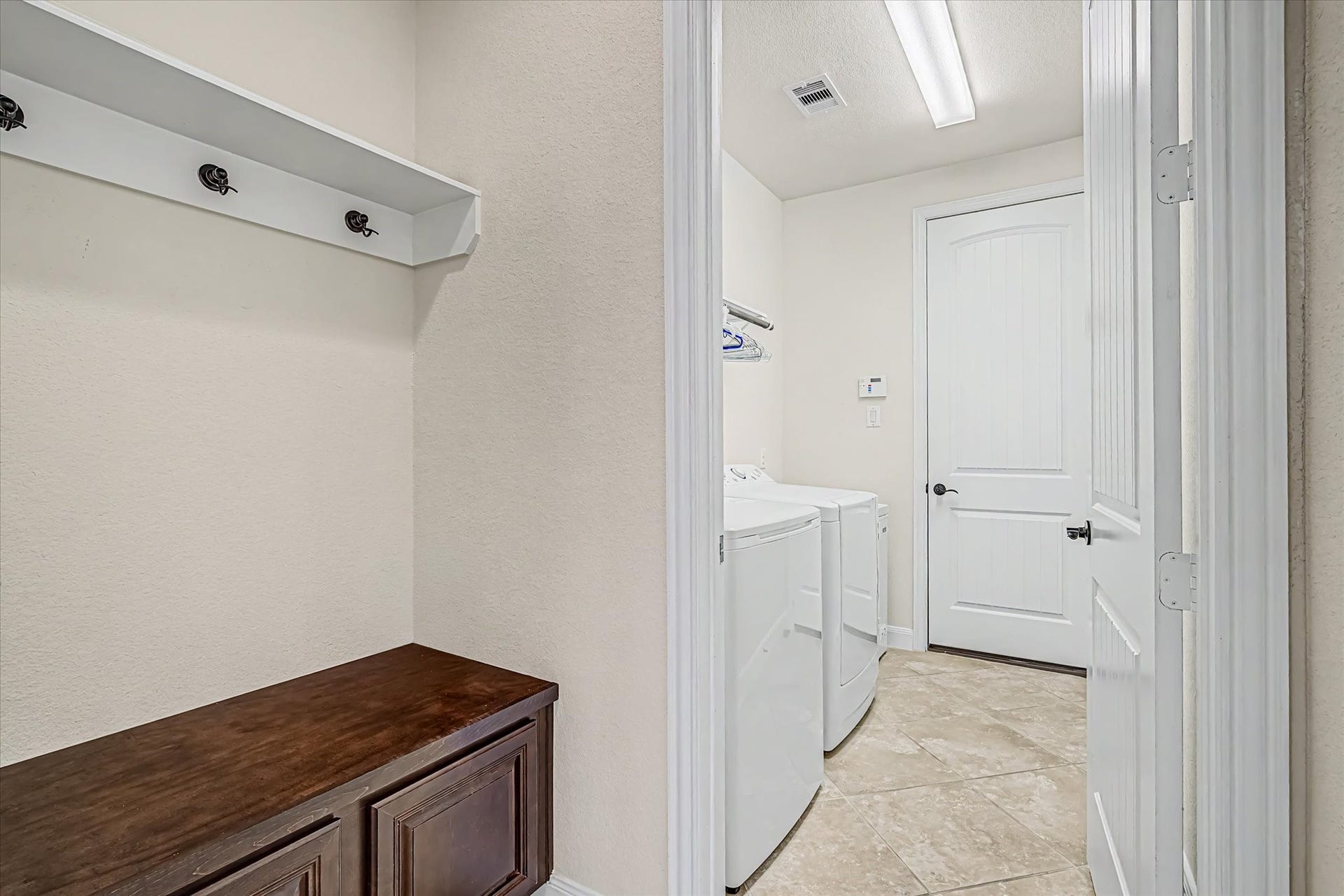 20302 Bandera Lake Lane, Richmond, TX 77407 Bright and functional laundry room with modern appliances, built-in storage, and convenient hanging space, all set on stylish tile flooring.