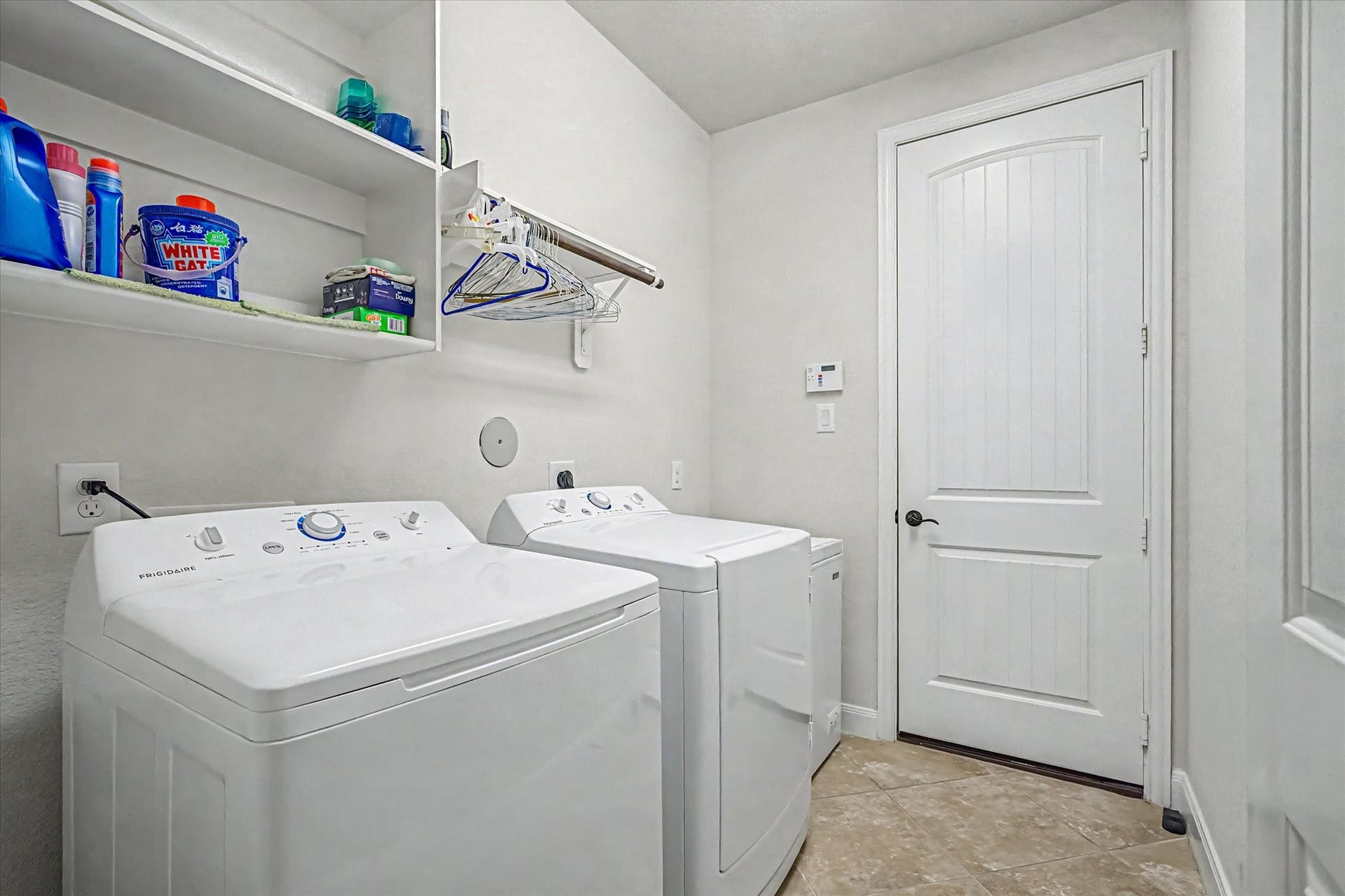 20302 Bandera Lake Lane, Richmond, TX 77407 A well-appointed laundry room featuring modern appliances, ample shelving, and a hanging rod for convenient organization.