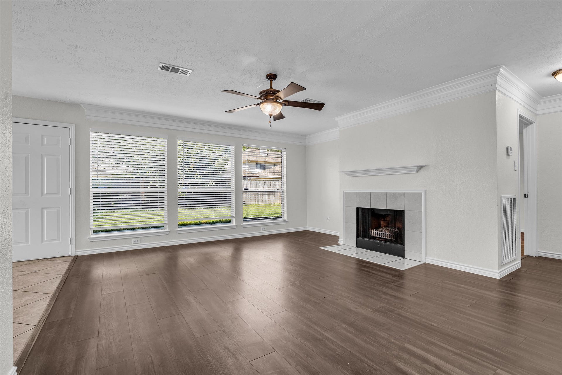 Gather around the tiled fireplace in a living room lined with windows to the backyard.