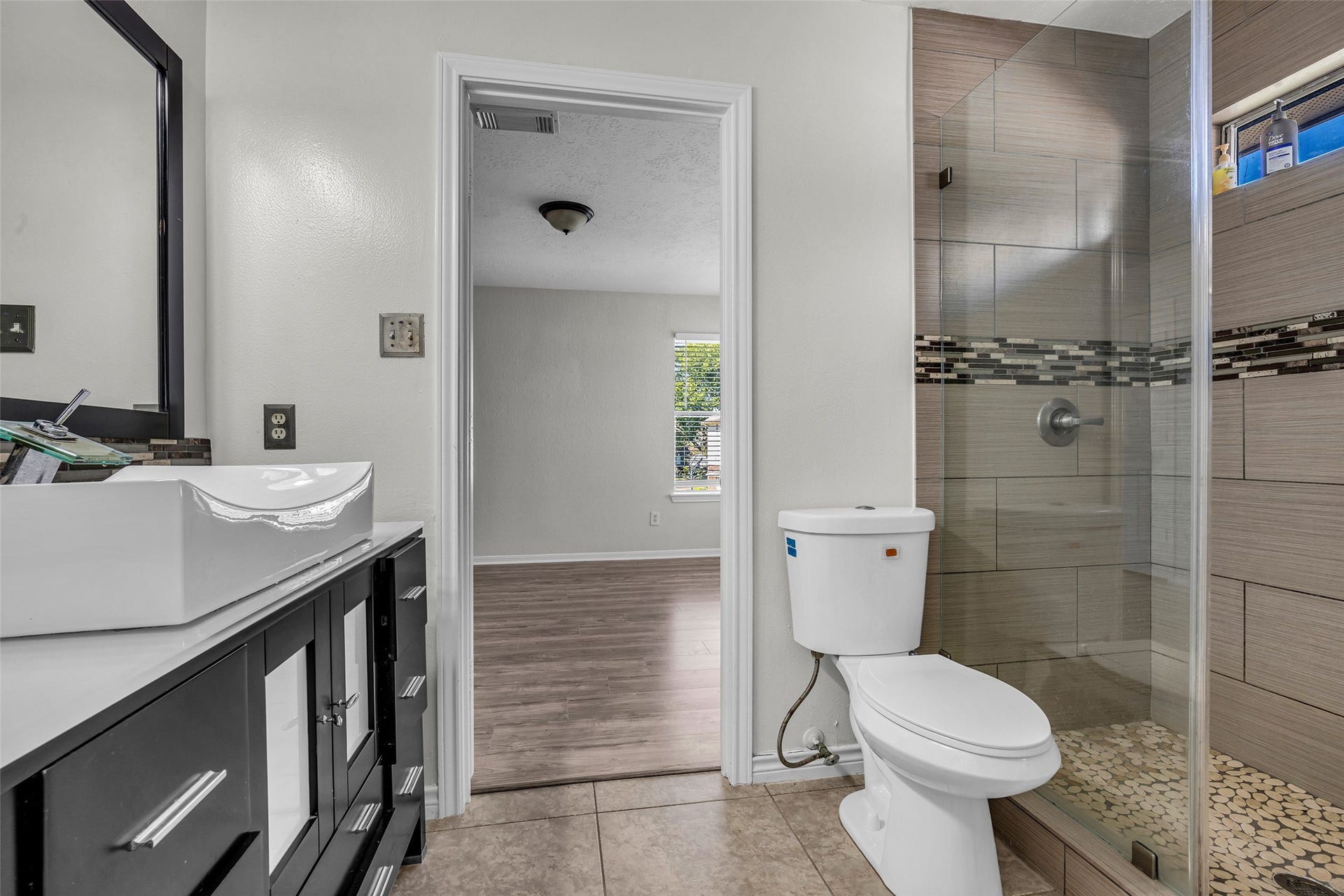 A full bath with a vessel sink, tiled walk-in shower and modern vanity.
