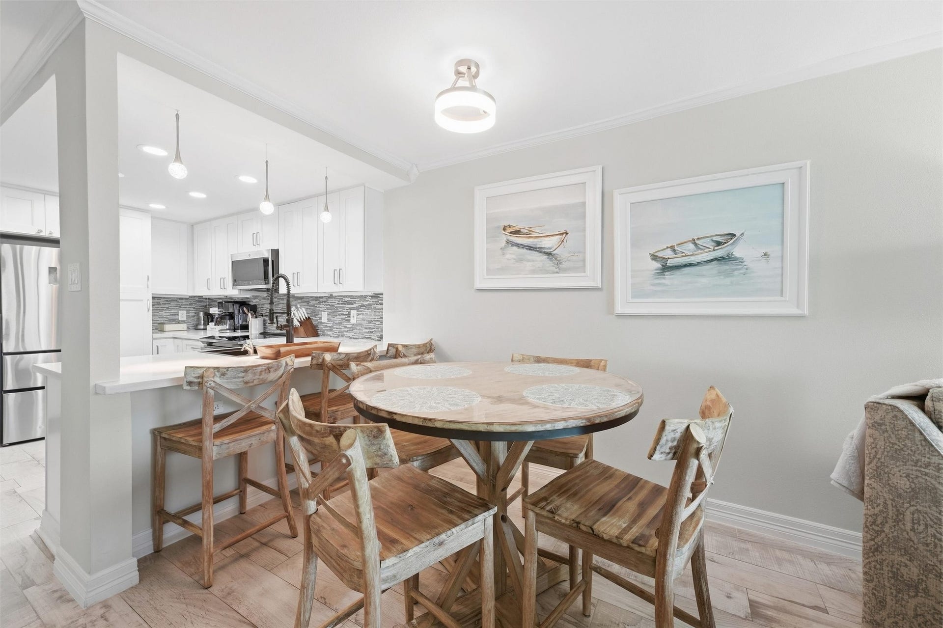7310 Seawall Boulevard, #1105, Galveston, TX 77551 Charming dining area with a rustic wooden table set, seamlessly connected to a modern kitchen featuring sleek cabinetry, stainless steel appliances, and stylish pendant lighting.
