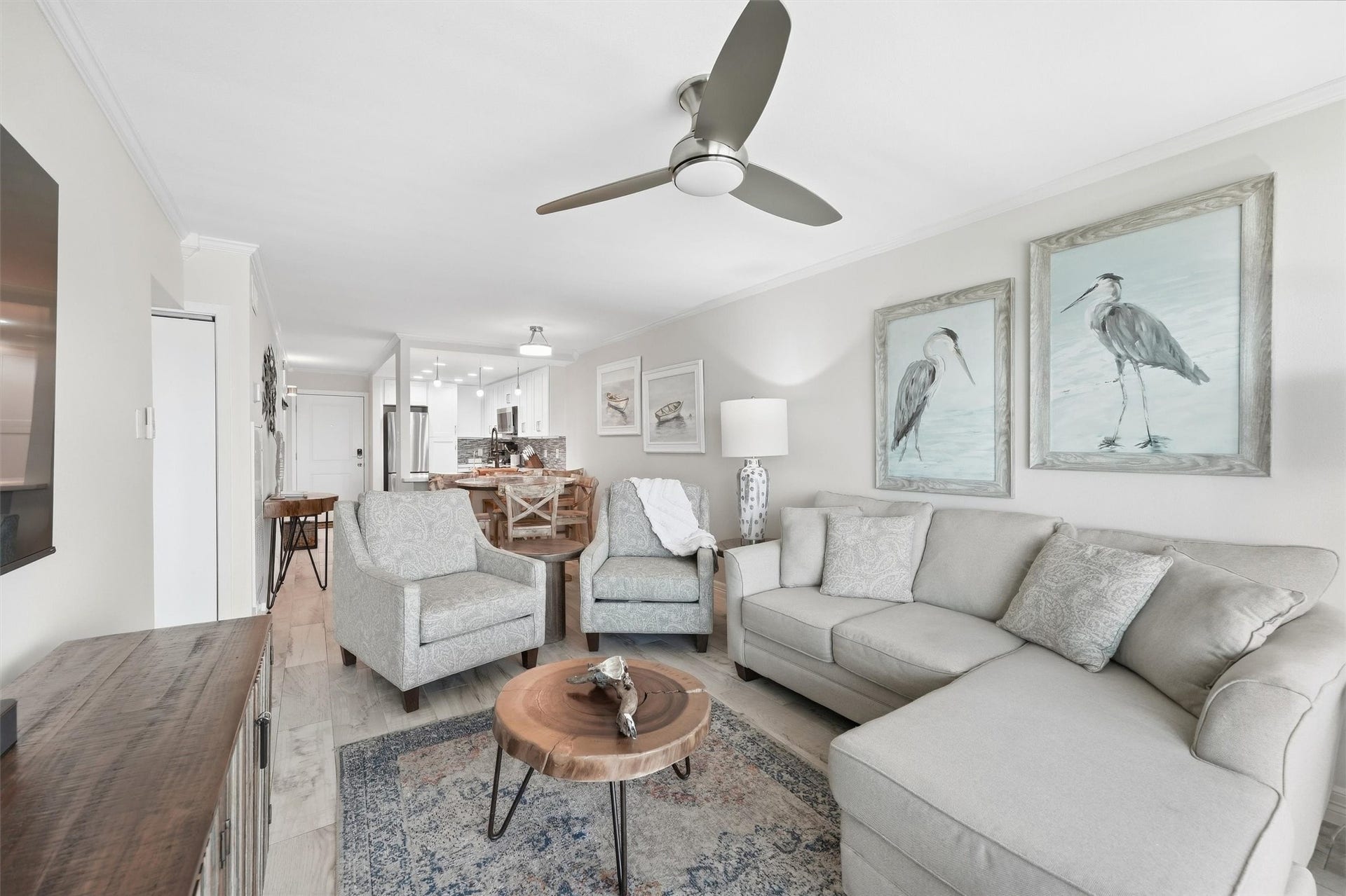 7310 Seawall Boulevard, #1105, Galveston, TX 77551 Chic and inviting, this open-concept living area boasts a cozy sectional sofa, stylish armchairs, and elegant artwork. The room seamlessly flows into a modern dining space and kitchen, perfect for entertaining.