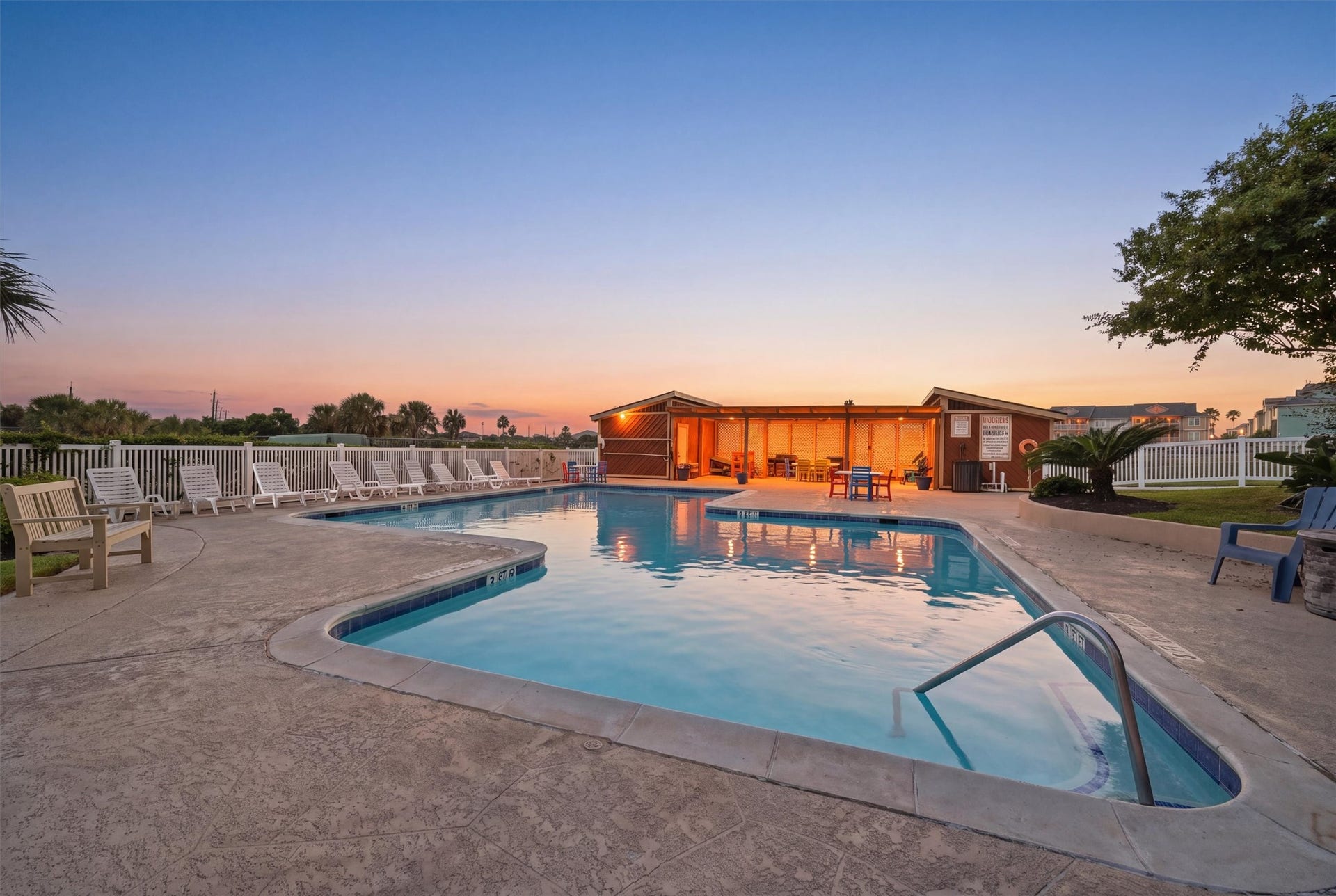 7310 Seawall Boulevard, #1105, Galveston, TX 77551 Relax and unwind in this inviting outdoor pool area, complete with ample seating and a picturesque sunset backdrop, perfect for evening gatherings.