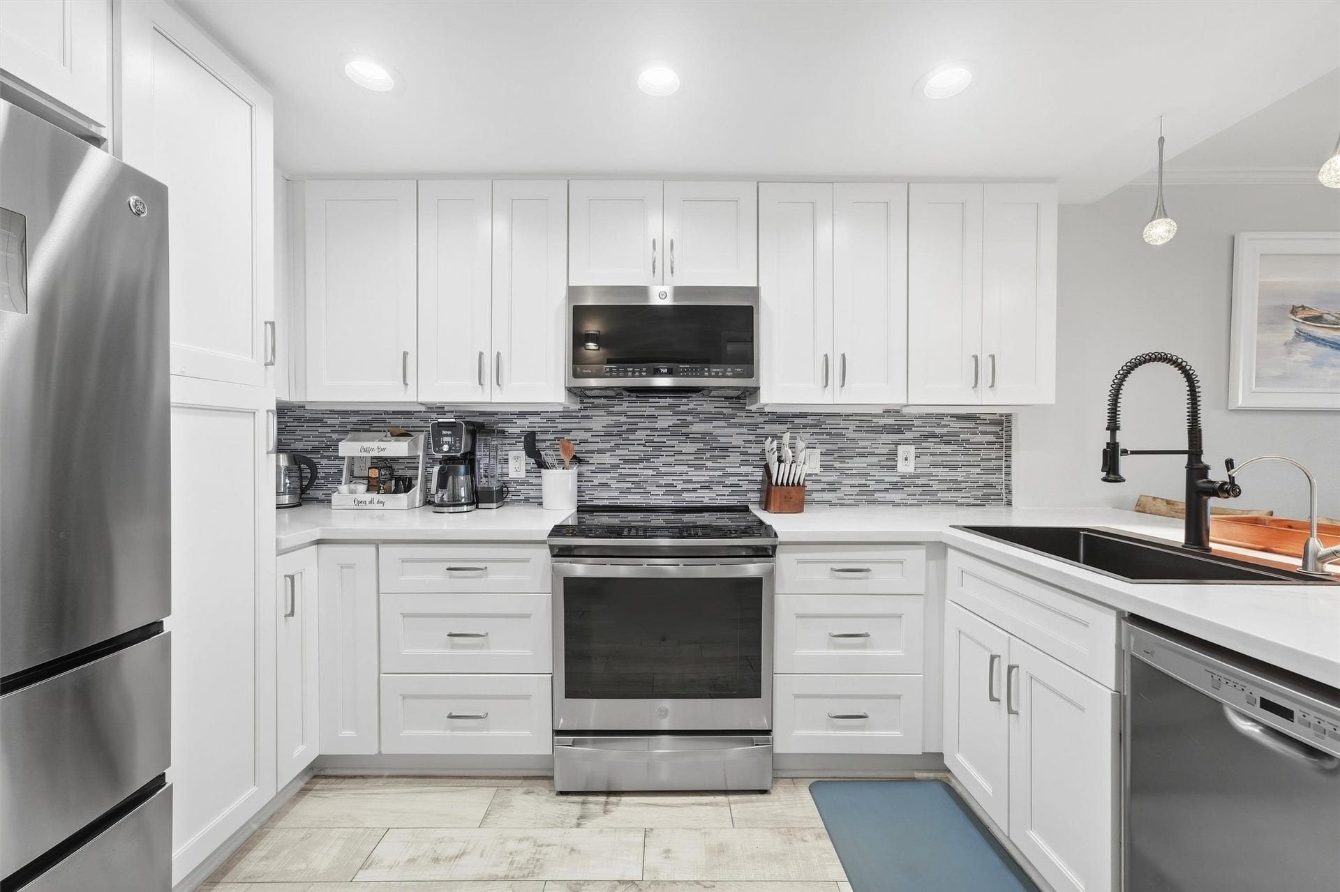 7310 Seawall Boulevard, #1105, Galveston, TX 77551 Modern kitchen with sleek stainless steel appliances, white cabinetry, and a stylish tile backsplash.