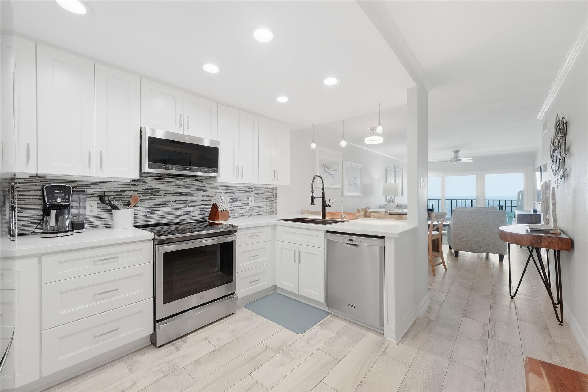 7310 Seawall Boulevard, #1105, Galveston, TX 77551 Sleek and modern kitchen with stainless steel appliances, bright white cabinetry, and a stylish tile backsplash. The space flows seamlessly into the open living area, perfect for entertaining.