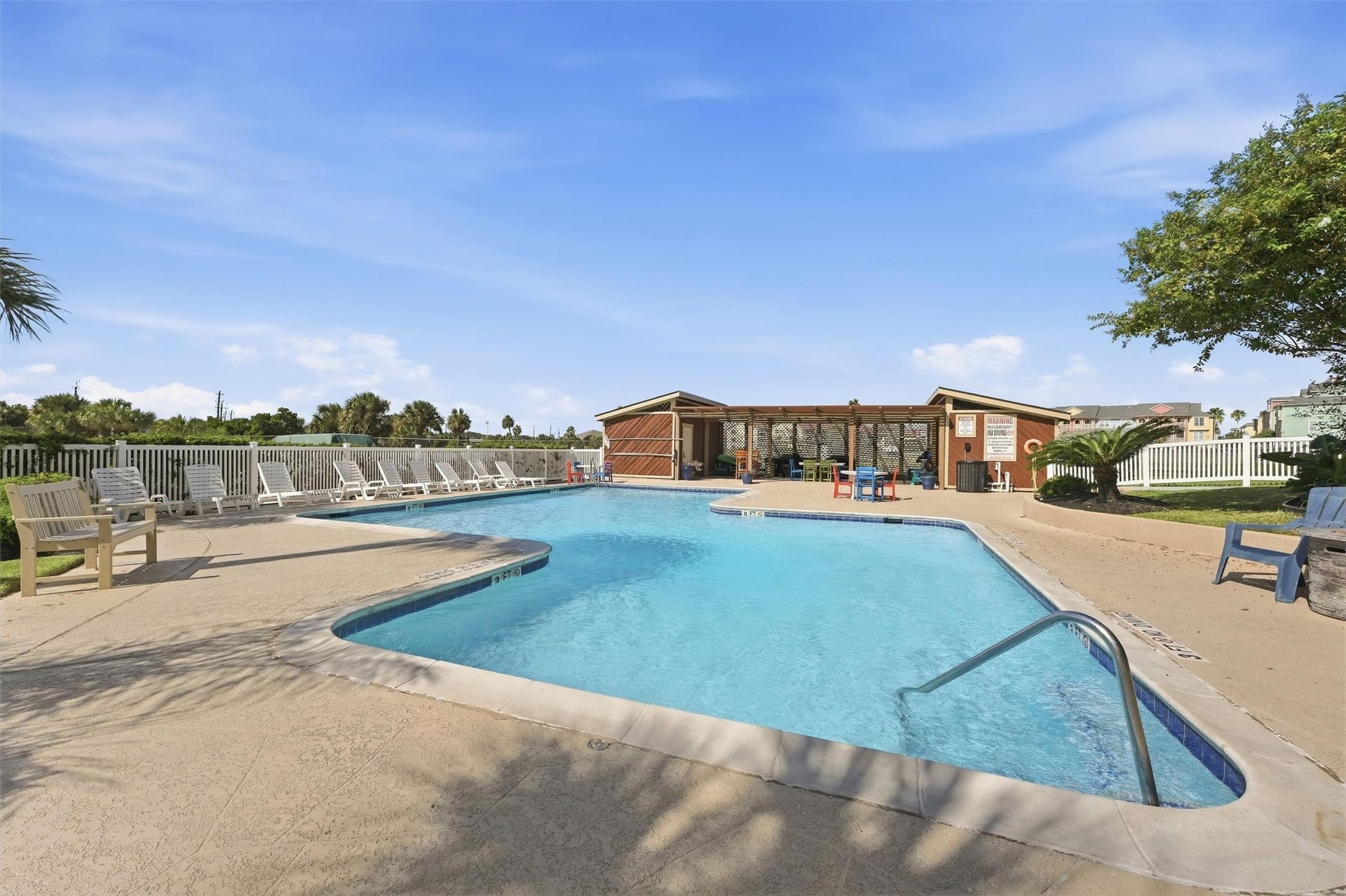 7310 Seawall Boulevard, #1105, Galveston, TX 77551 Relax and unwind in this inviting outdoor pool area, featuring a spacious deck with plenty of loungers and a cozy clubhouse for refreshments.