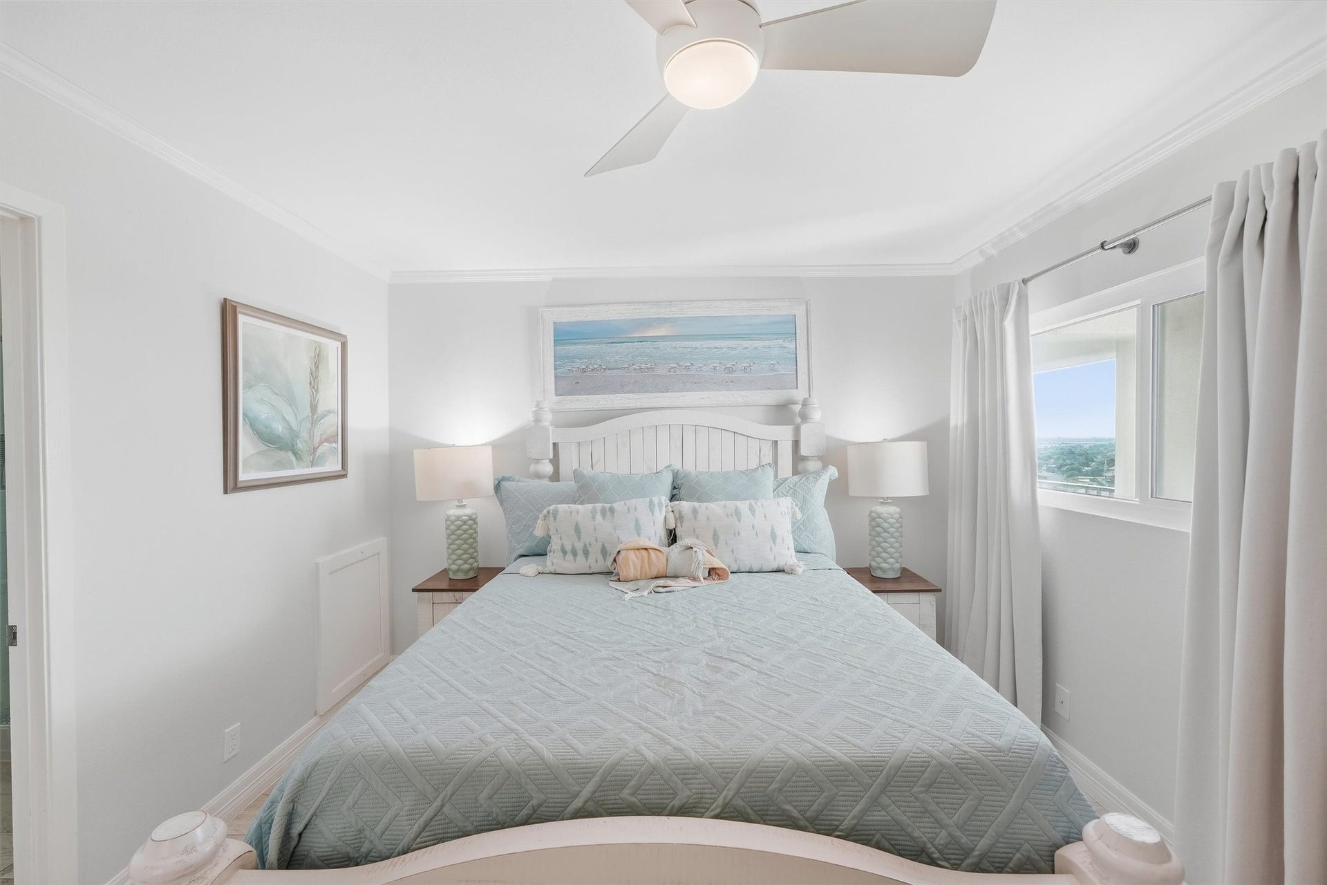 7310 Seawall Boulevard, #1105, Galveston, TX 77551 Bright and serene bedroom featuring a comfortable bed with stylish bedding, coastal artwork, and ample natural light from a large window.