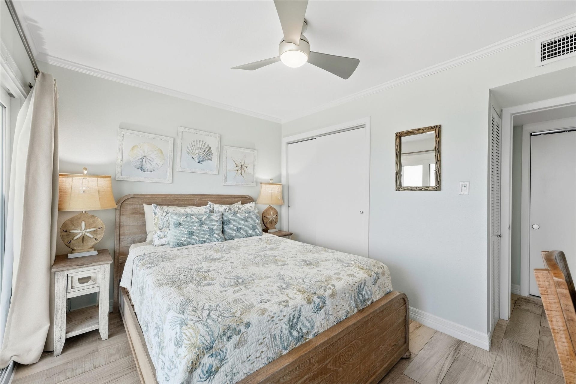 7310 Seawall Boulevard, #1105, Galveston, TX 77551 Cozy bedroom featuring a comfortable bed with coastal-themed decor, soft lighting from matching lamps, and a ceiling fan for comfort.